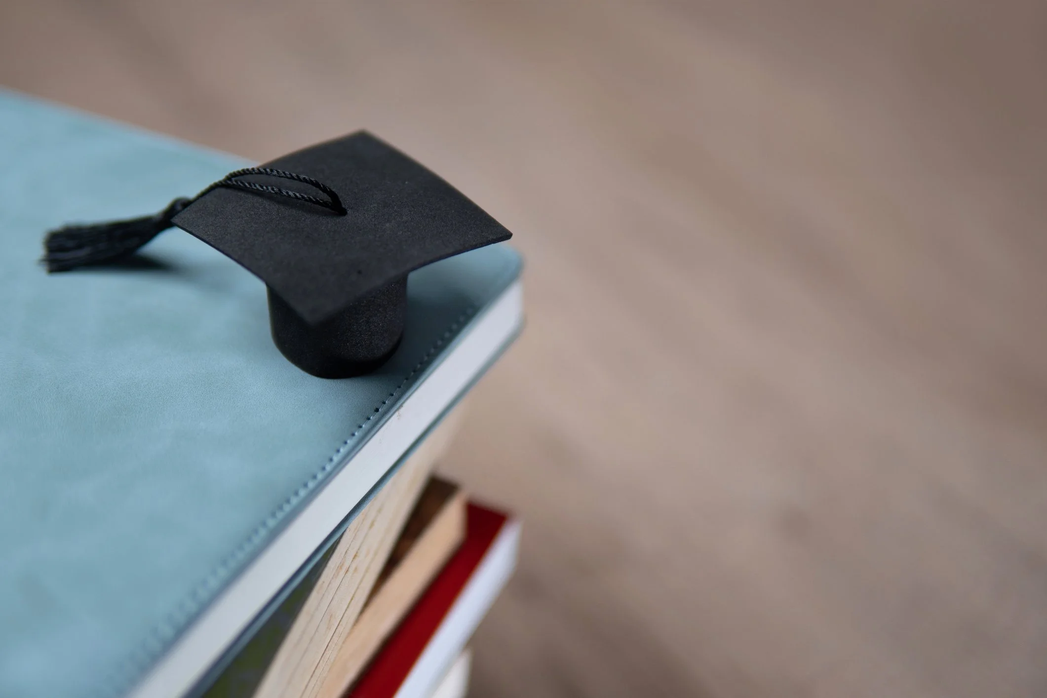 Tiny graduation cap on top of a stack of books