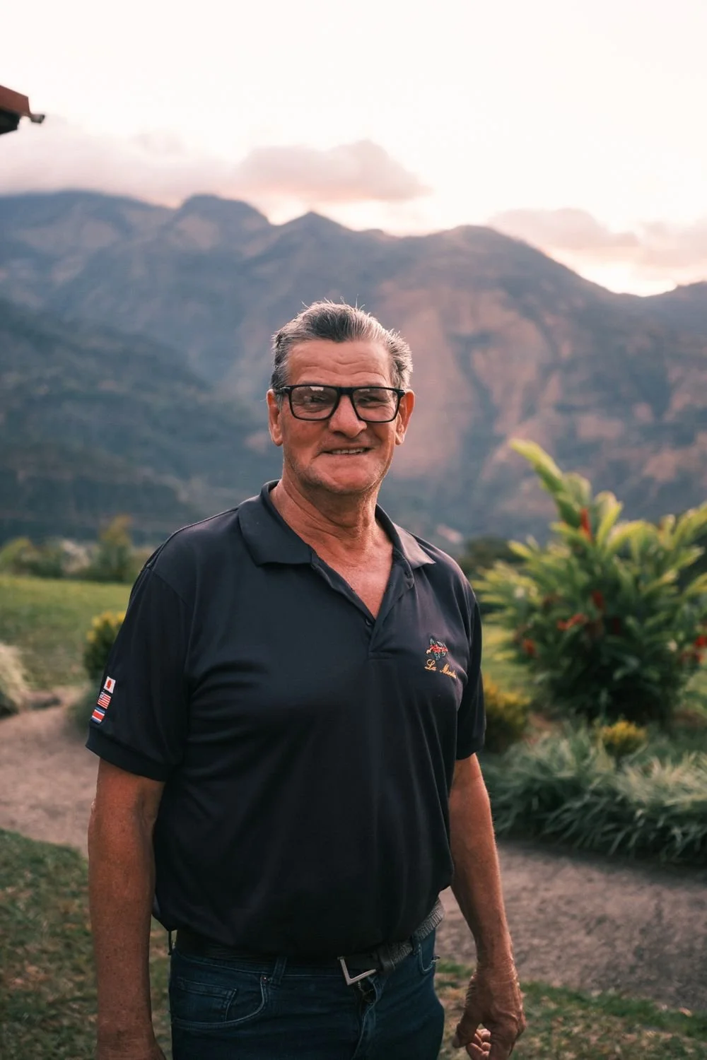 A longtime La Minita farmer smiling at dusk with the mountains behind him