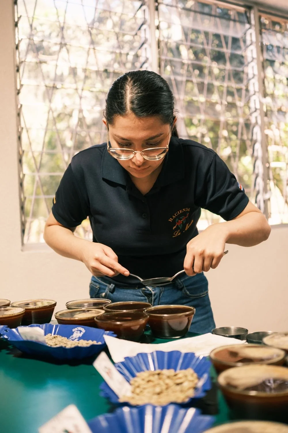 A La Minita cupper skimming a cupping bowl with two spoons