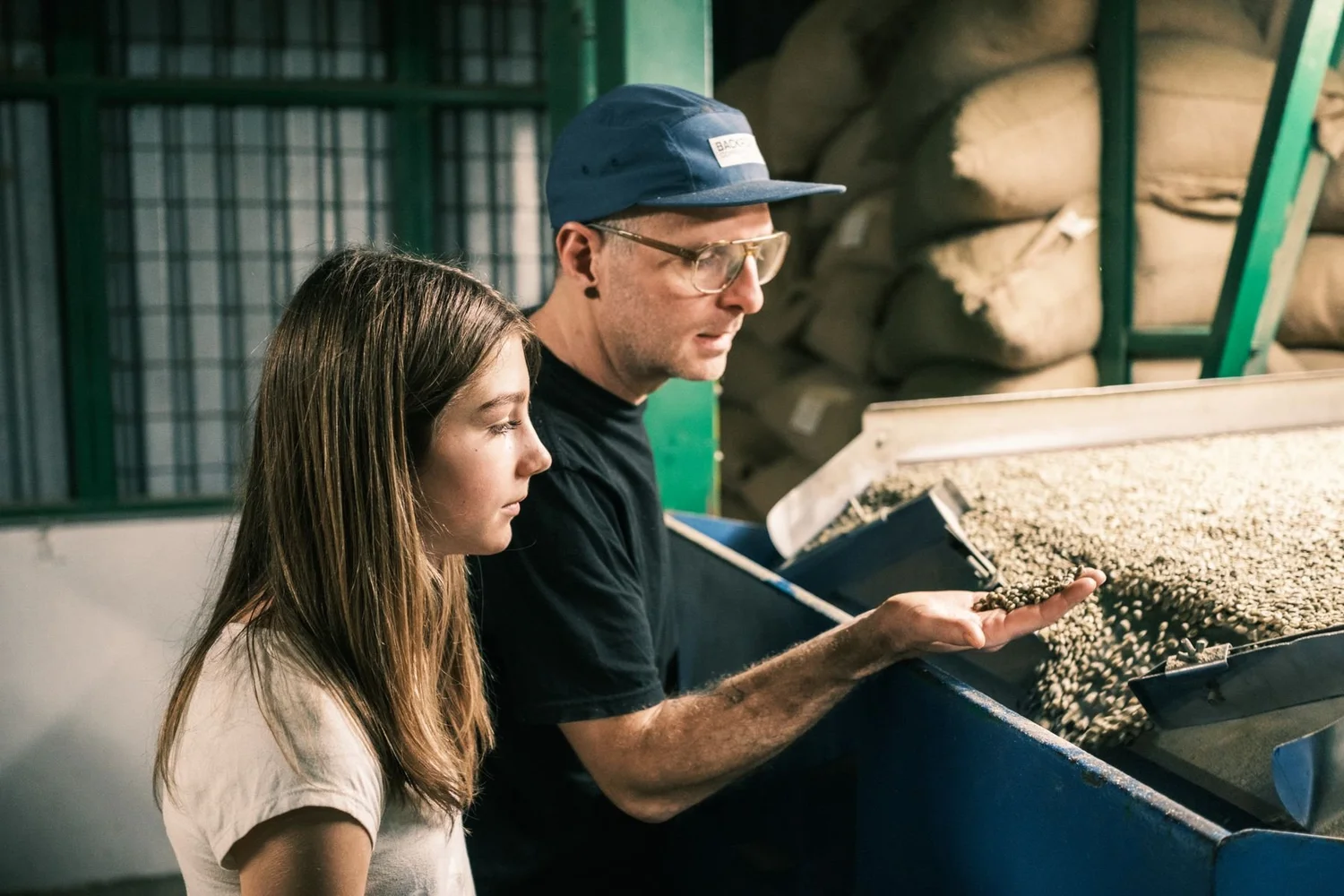 Dave Beach showing his daughter Scout green coffee at the dry mill