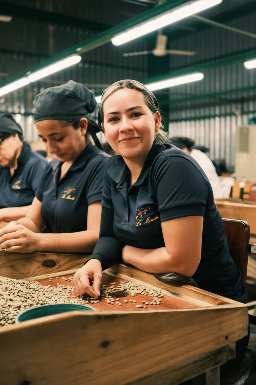A sorter at the mill smiling up from her tray of green coffee