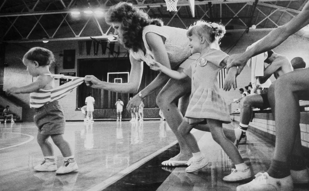 A pair of kids make a run for their dad while watching a men's three-on-three tournament in Ferdinand, IN.