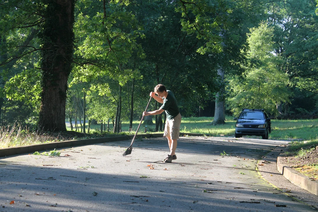 Mike Mueller sweeps the course after a Saturday storm left an abundance of debris.