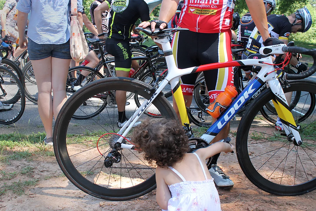 Seconds before the start of her father's race, Lucille Bota, 3, plays with his bike. Louis Botta was waiting for his wife, Jamie, after she completed her race.