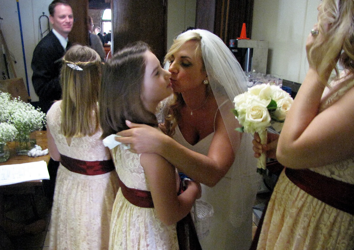 Bride Frances Crawford gives a quick kiss to her sister, Zoe Myers, in a wedding venue kitchen before walking down the aisle.