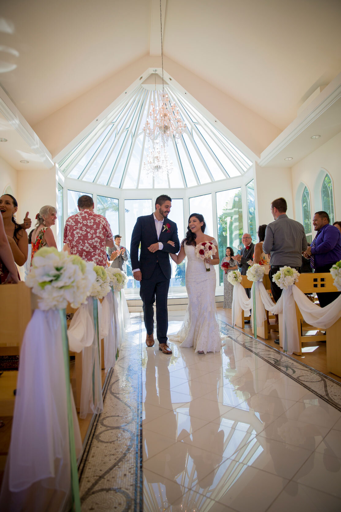 newlyweds-walking-down-aisle-at-paradise-cove-crystal-chapel-hawaii.jpg