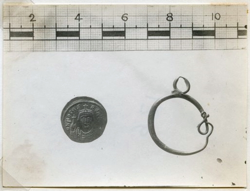 Photograph of the earring and a coin found in the debris of House III.