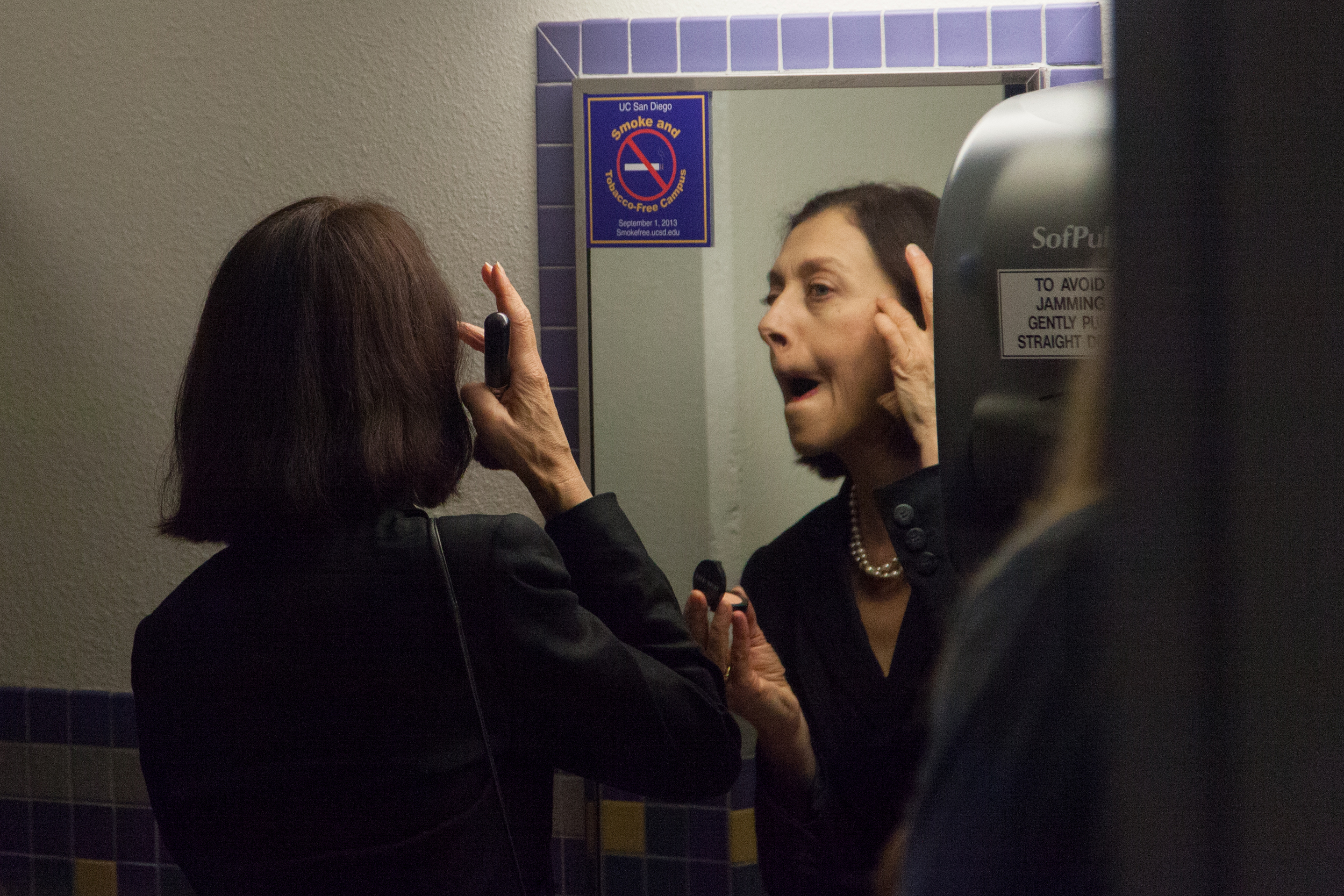 Gertrude (Eva Barnes) gives beauty advice to the audience in the bathroom.