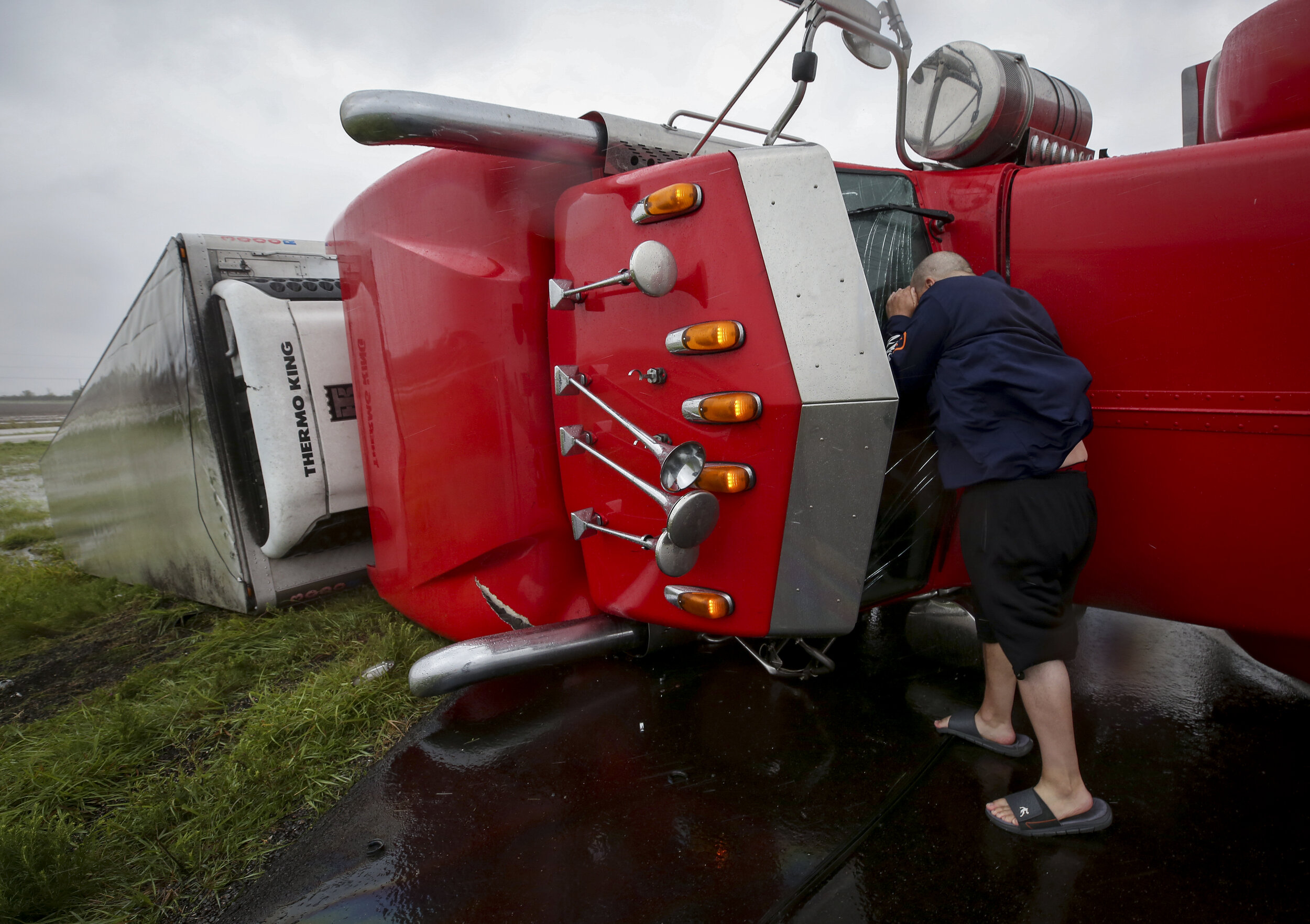  Dave McGrew looks into the cabin of an 18-wheeler that was flipped on its side on Highway 59 West as Hurricane Harvey made landfall in the Central Gulf Coast on Saturday, Aug. 26, 2017, in Texas. Mcgrew stopped while on his way to check on his famil