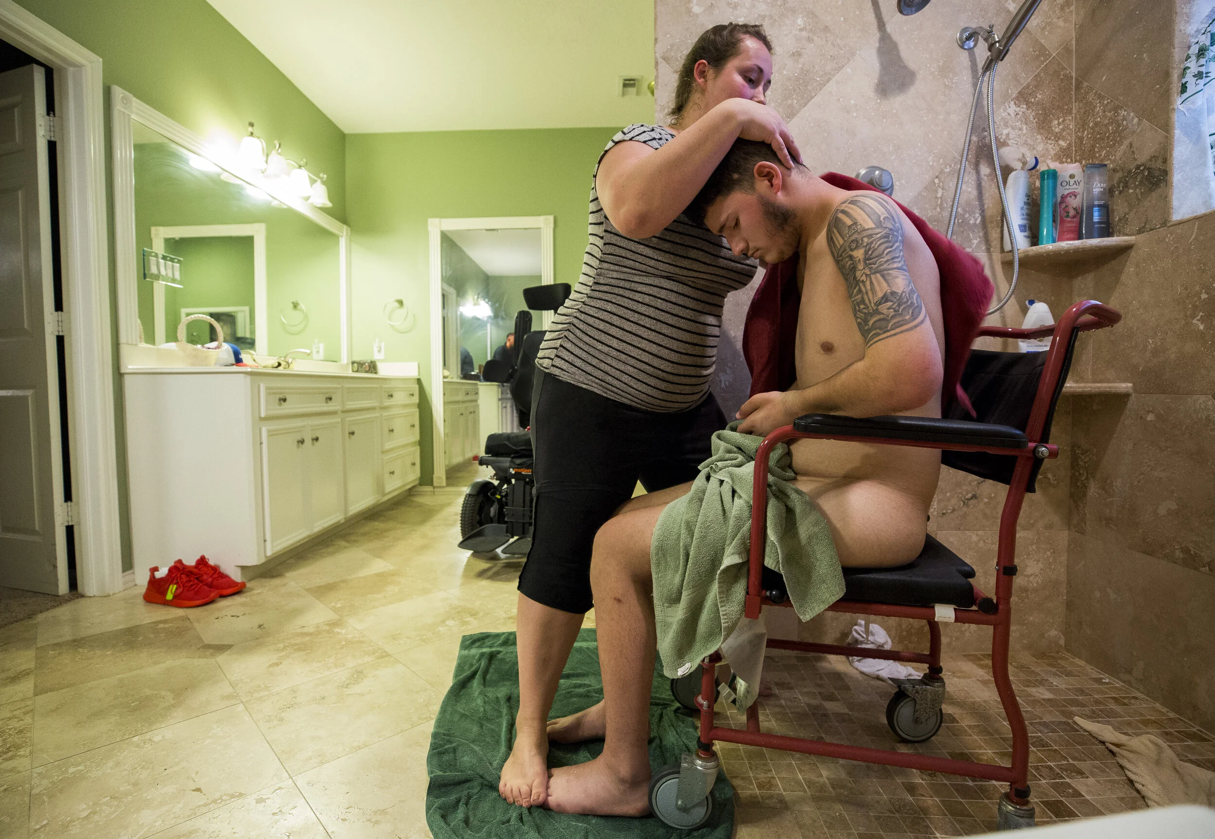  Kristin Petty uses her feet to keep David Jacob Anzaldua, better known as D.J., from sliding off his chair while she dries him off after a shower. D.J., 19, fell asleep while driving in Jewett, Texas. He suffered a C4 spinal cord injury that left hi