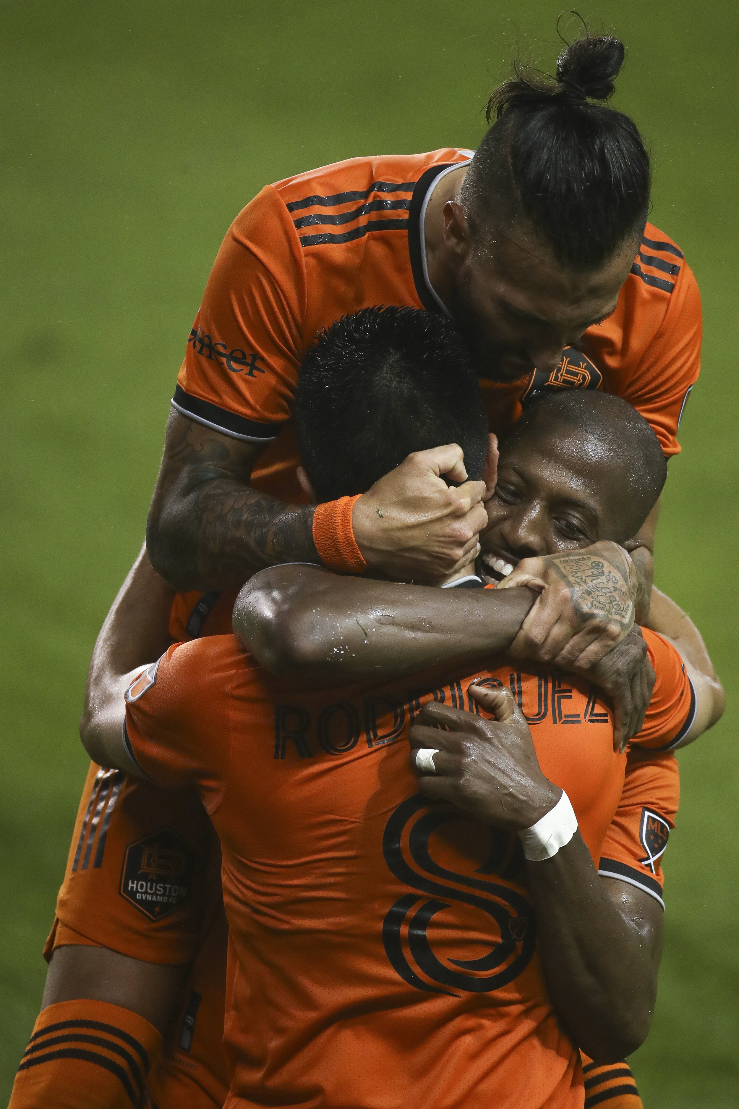  Houston Dynamo FC midfielder Memo Rodriguez (8) is hugged by forward Maximiliano Urruti (37), top, and  midfielder Fafa Picault (10) after he scored a goal against the San Jose Earthquakes during the first half of an MLS match at BBVA Stadium on Fri