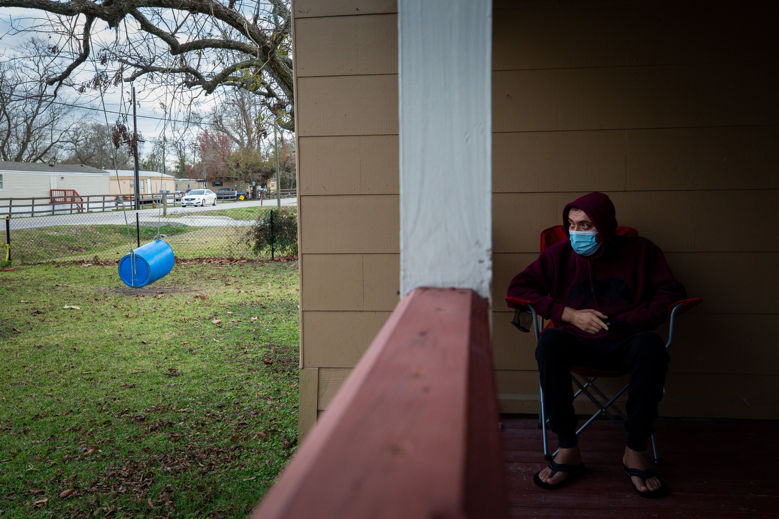  Jesus sits on the porch as motorists drive past his home on Tuesday, Jan. 4, 2022, in Baytown, Texas. Now restricted from working, he thinks about what the future holds for him and his family. 