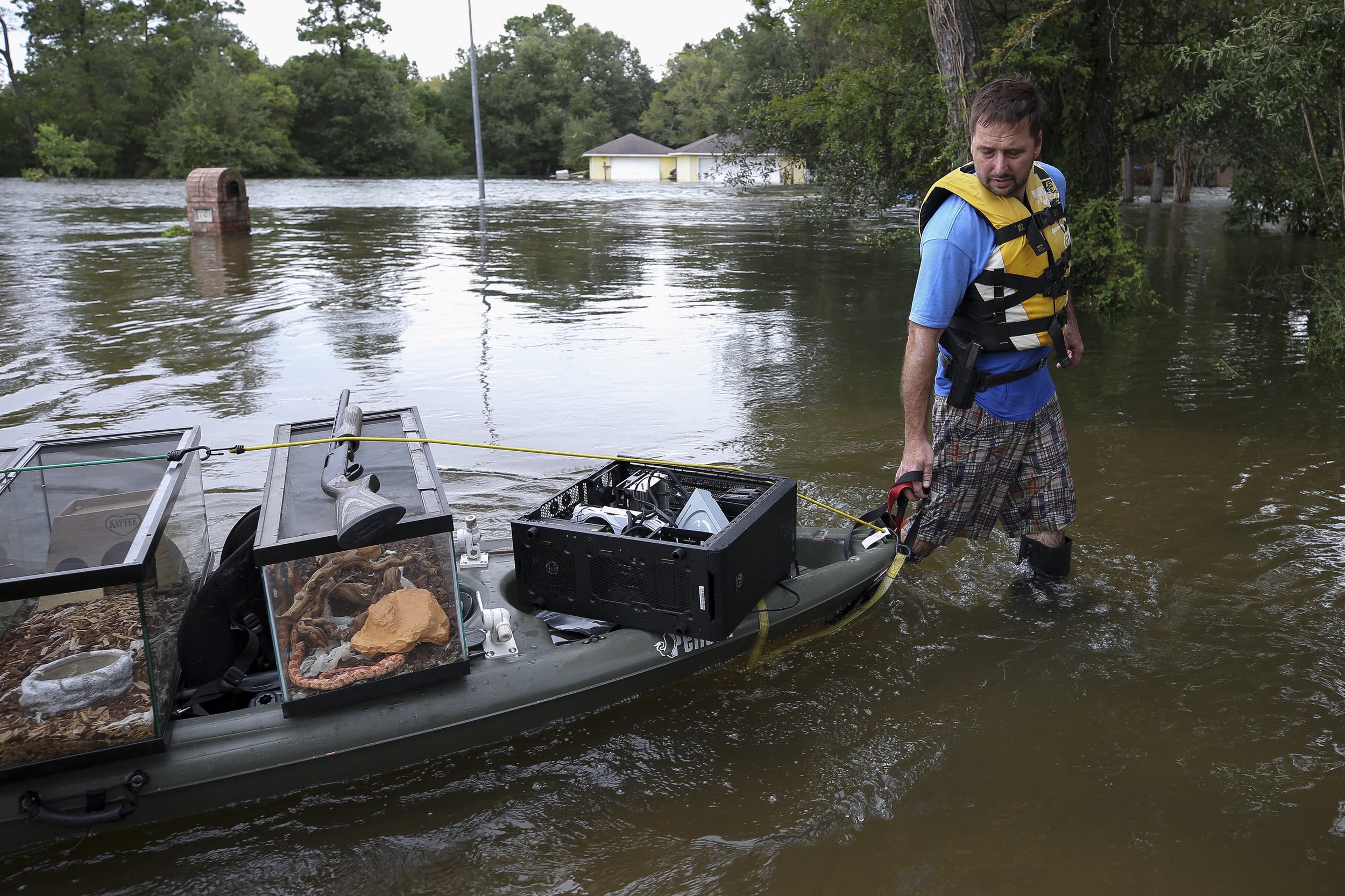  Alen Pogue drags a kayak carrying three pet snakes, a leopard gecko, and firearms after returning from his flooded home during Hurricane Harvey on Wednesday, Aug. 30, 2017, in Baytown, Texas. 