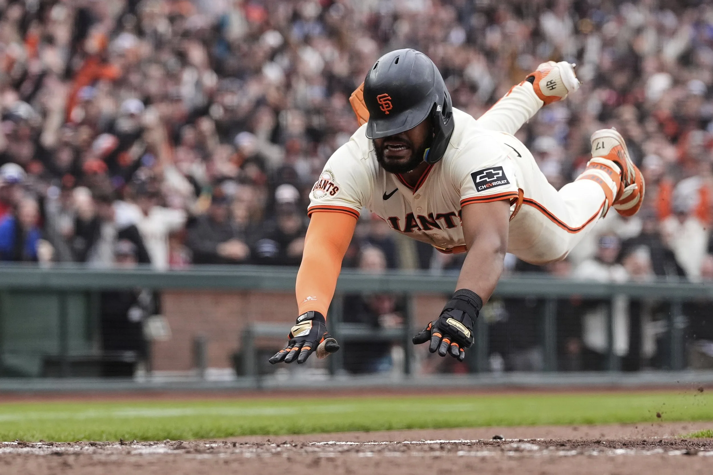 San Francisco Giants' Heliot Ramos dives home to score the game-winning run on a throwing error Texas Rangers first baseman Jake Burger during the ninth inning of a baseball game Sunday, April 27, 2025, in San Francisco. (AP Photo/Godofredo A. Vásqu