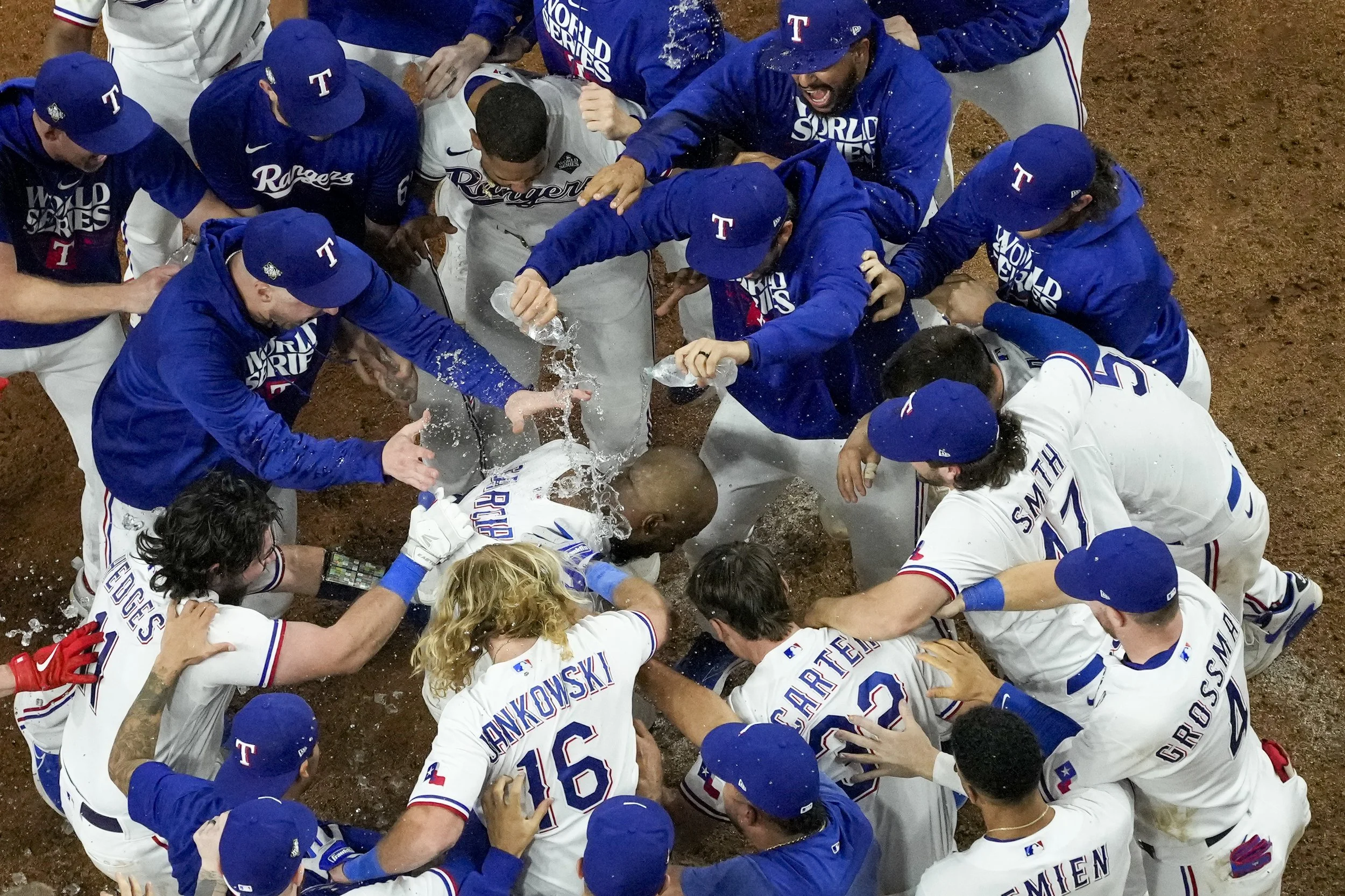 Texas Rangers' Adolis Garcia, center, is mobbed by teammates after hitting a game-winning home run against the Arizona Diamondbacks during the 11th inning in Game 1 of the baseball World Series, Friday, Oct. 27, 2023, in Arlington, Texas. The Ranger