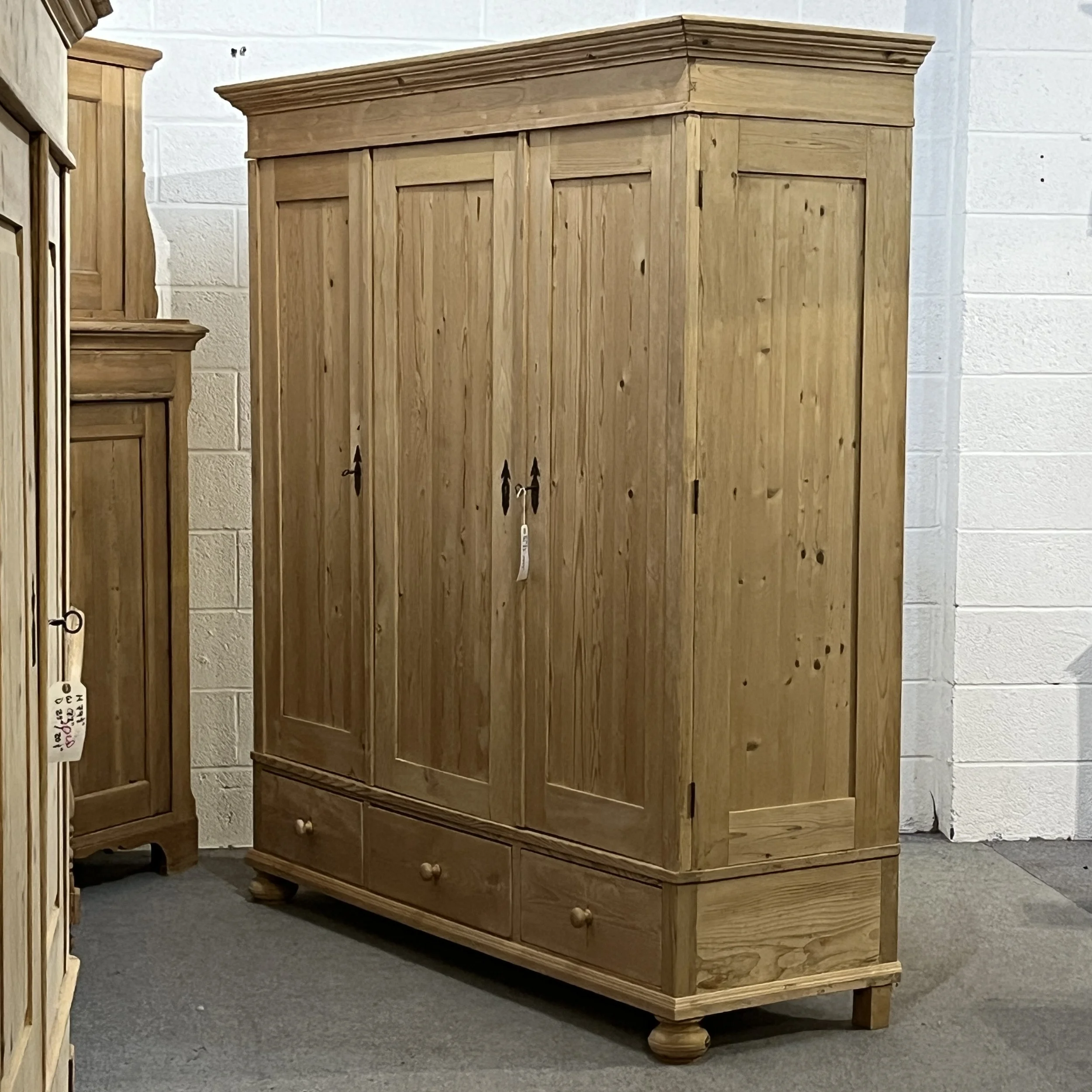 Angled view of the triple pine wardrobe showing its right side and bottom drawers