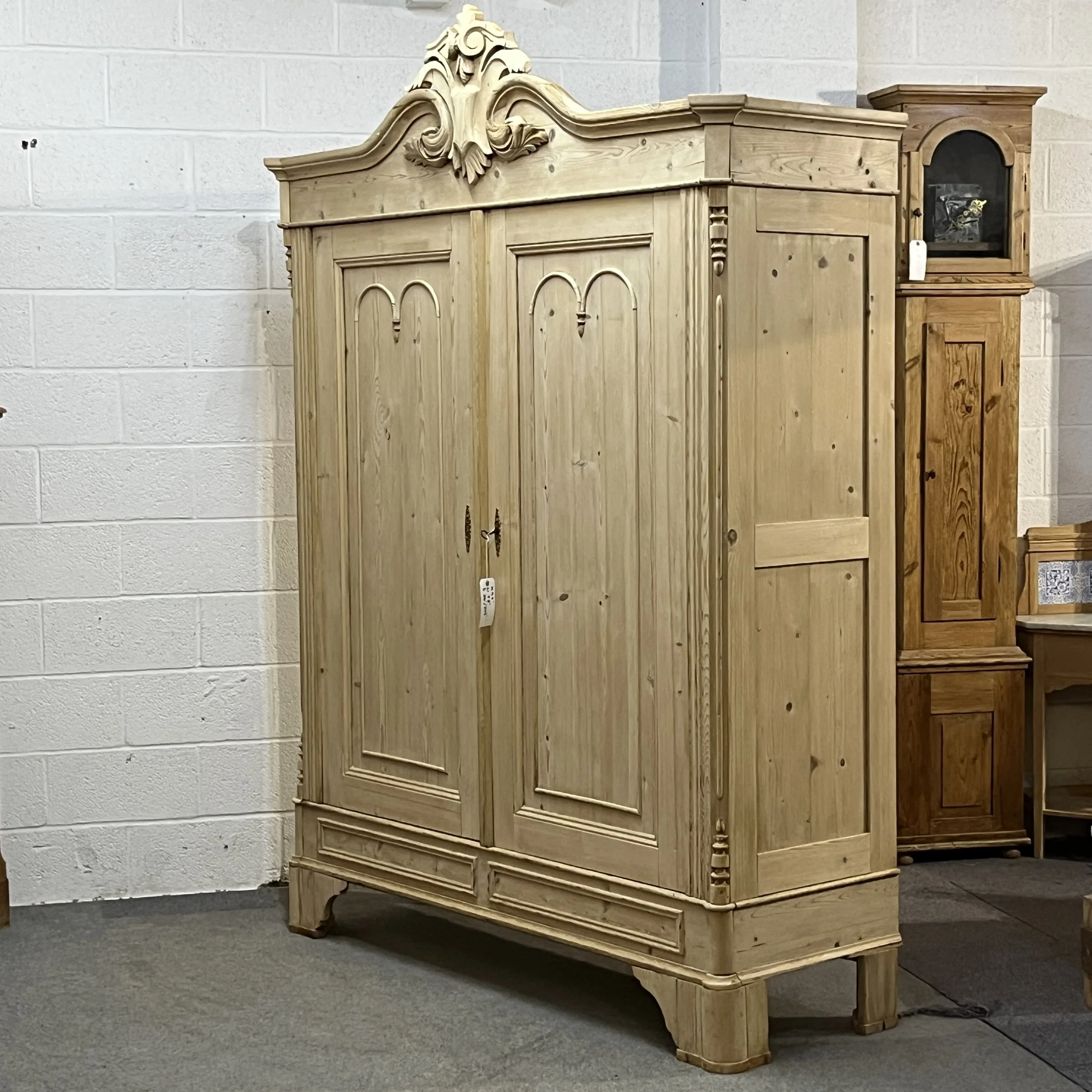 Angled view of the large double pine wardrobe showing its side and carved crest