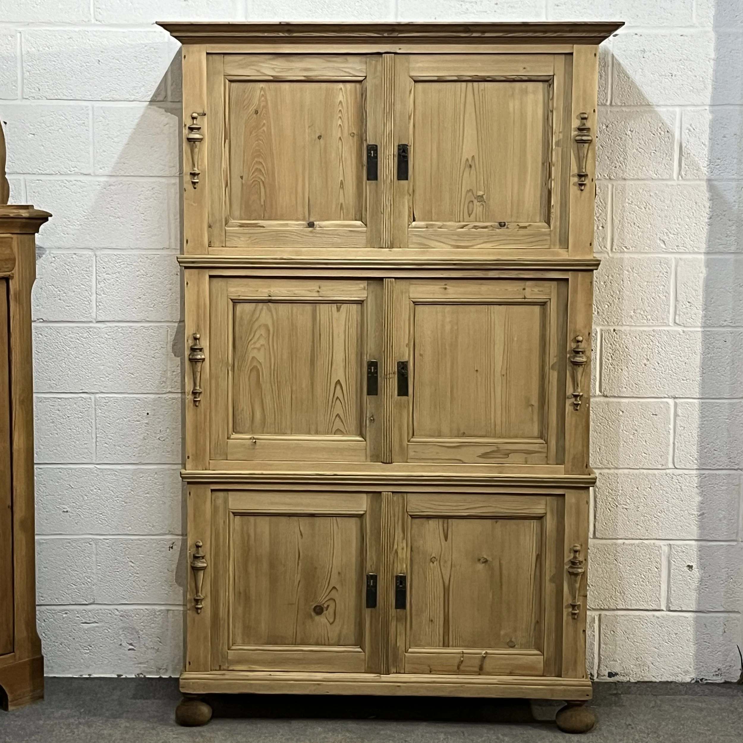 Front view of the tall pine campaign cupboard with three stacked pairs of doors