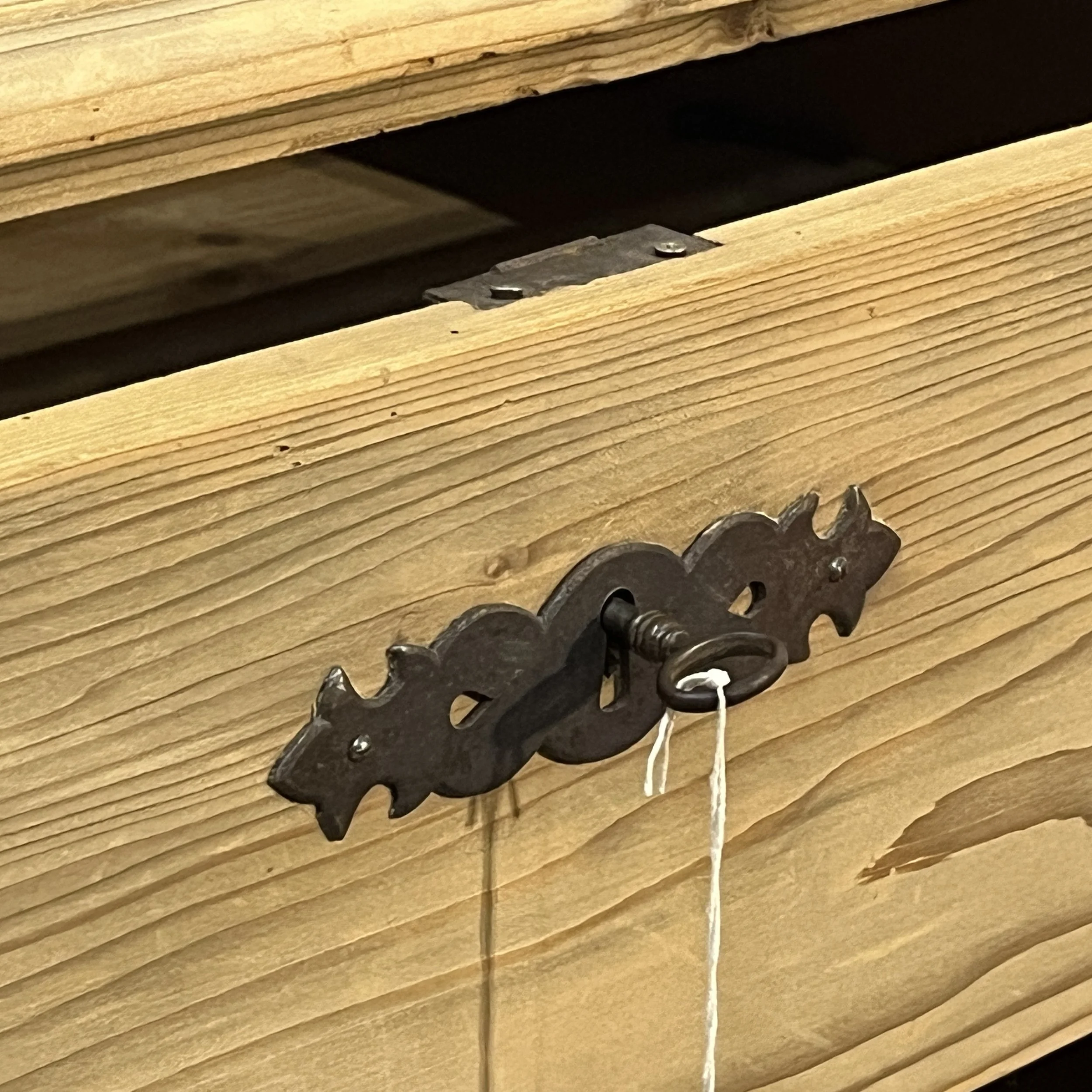 Close-up of decorative metal escutcheon and key on antique pine chest N7308C
