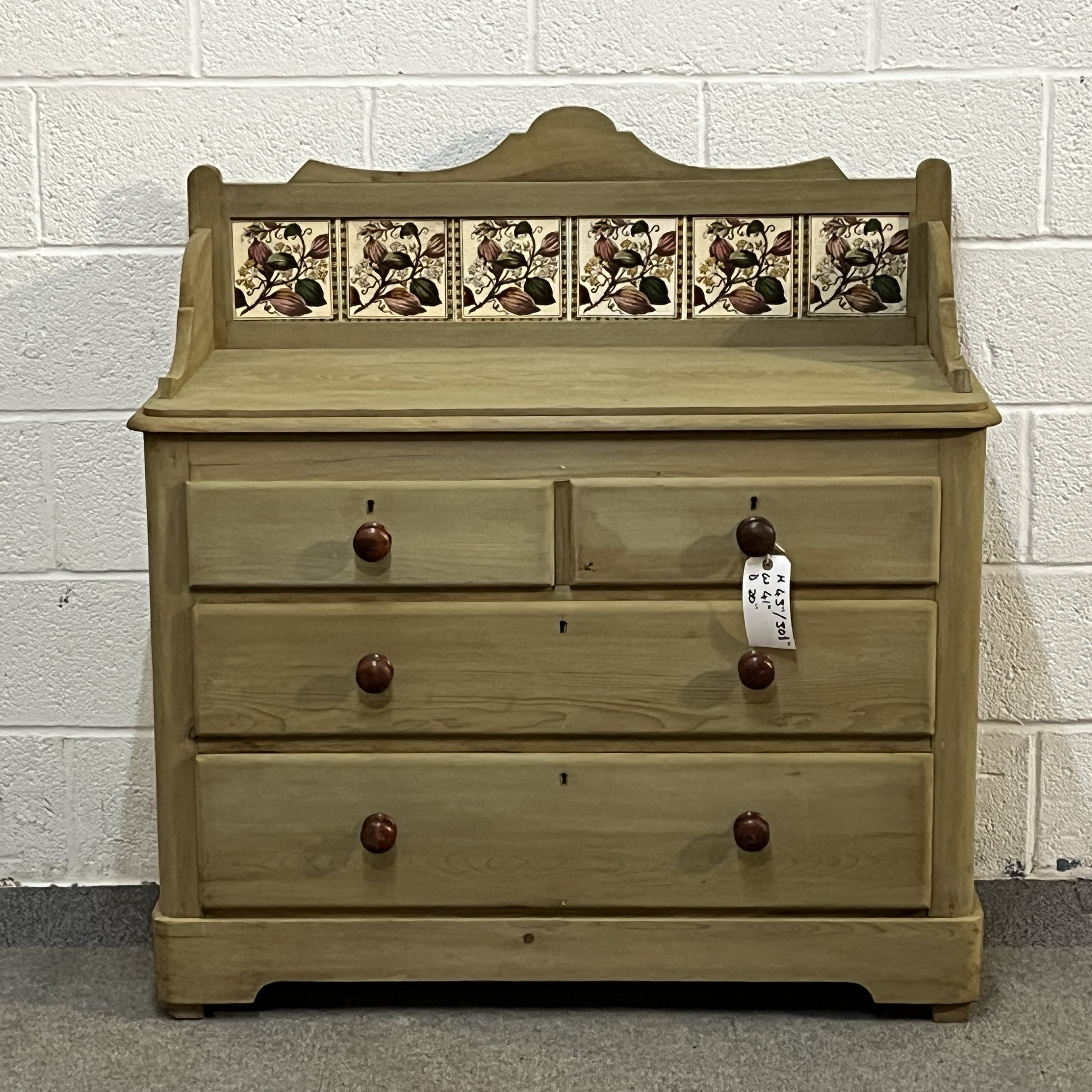 Closer front view of the Victorian pine chest of drawers and six original floral tiles