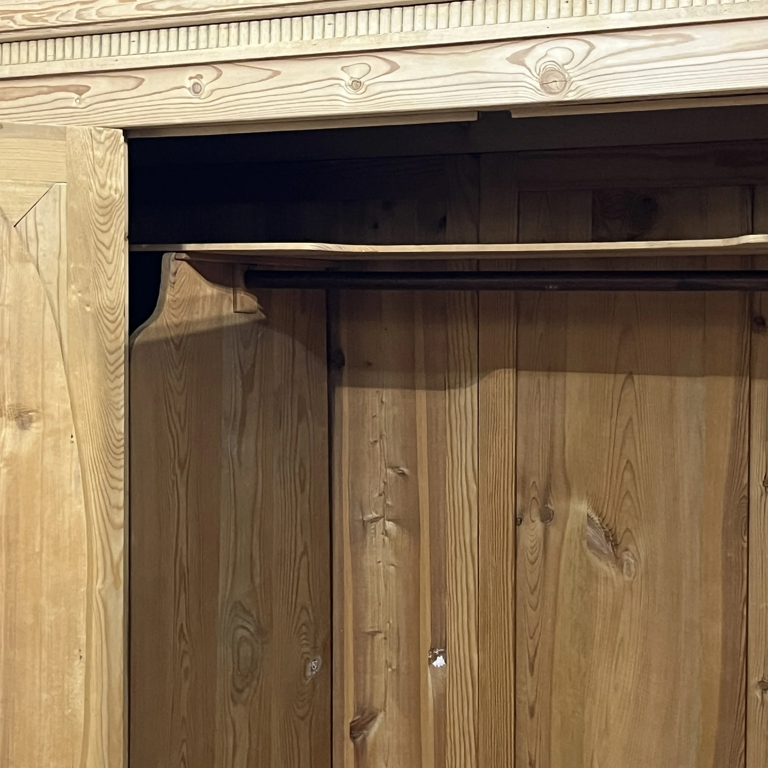 Pine wardrobe upper hanging compartment with wooden rail visible