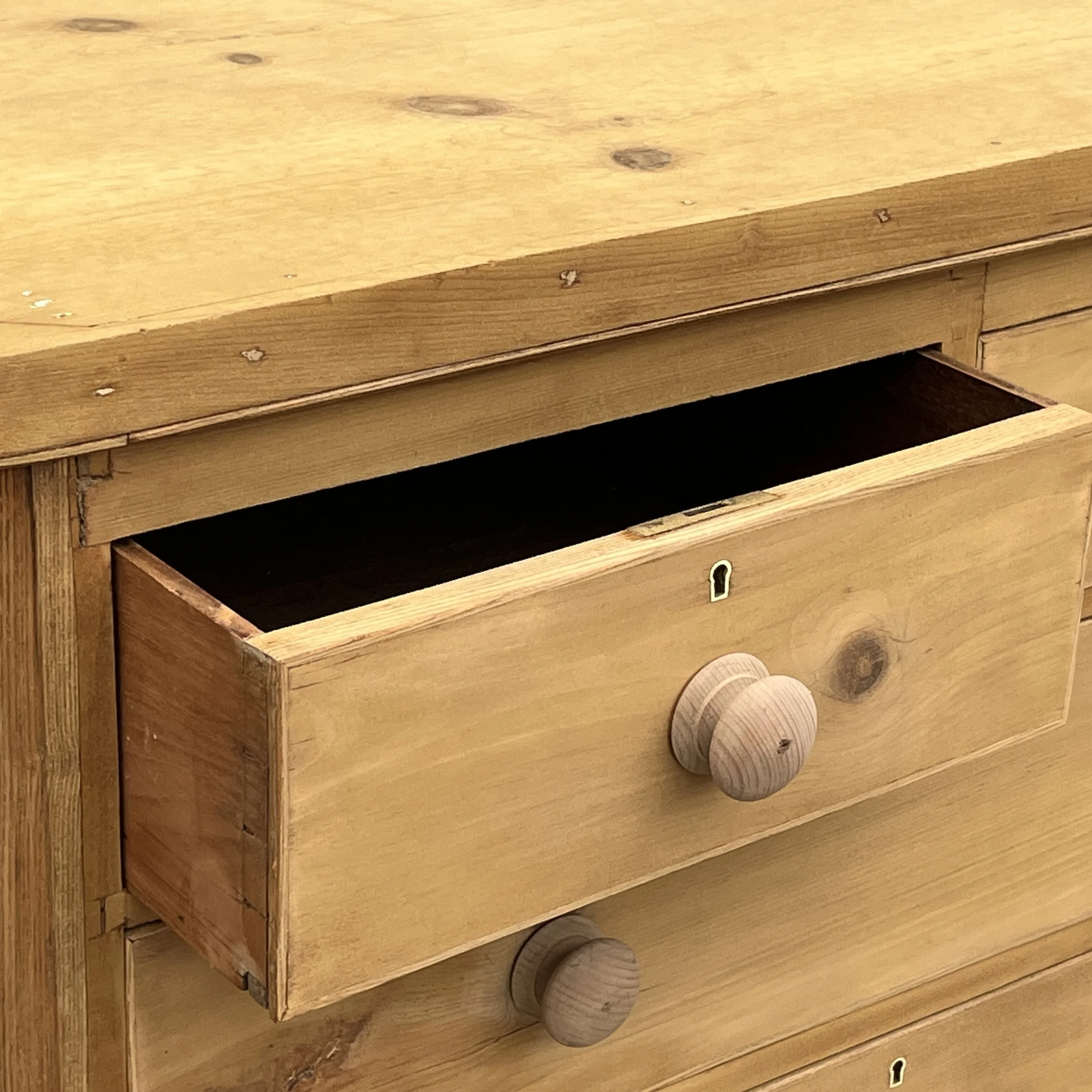 Detail of an open upper drawer, wooden knob and keyhole on pine chest N8709E