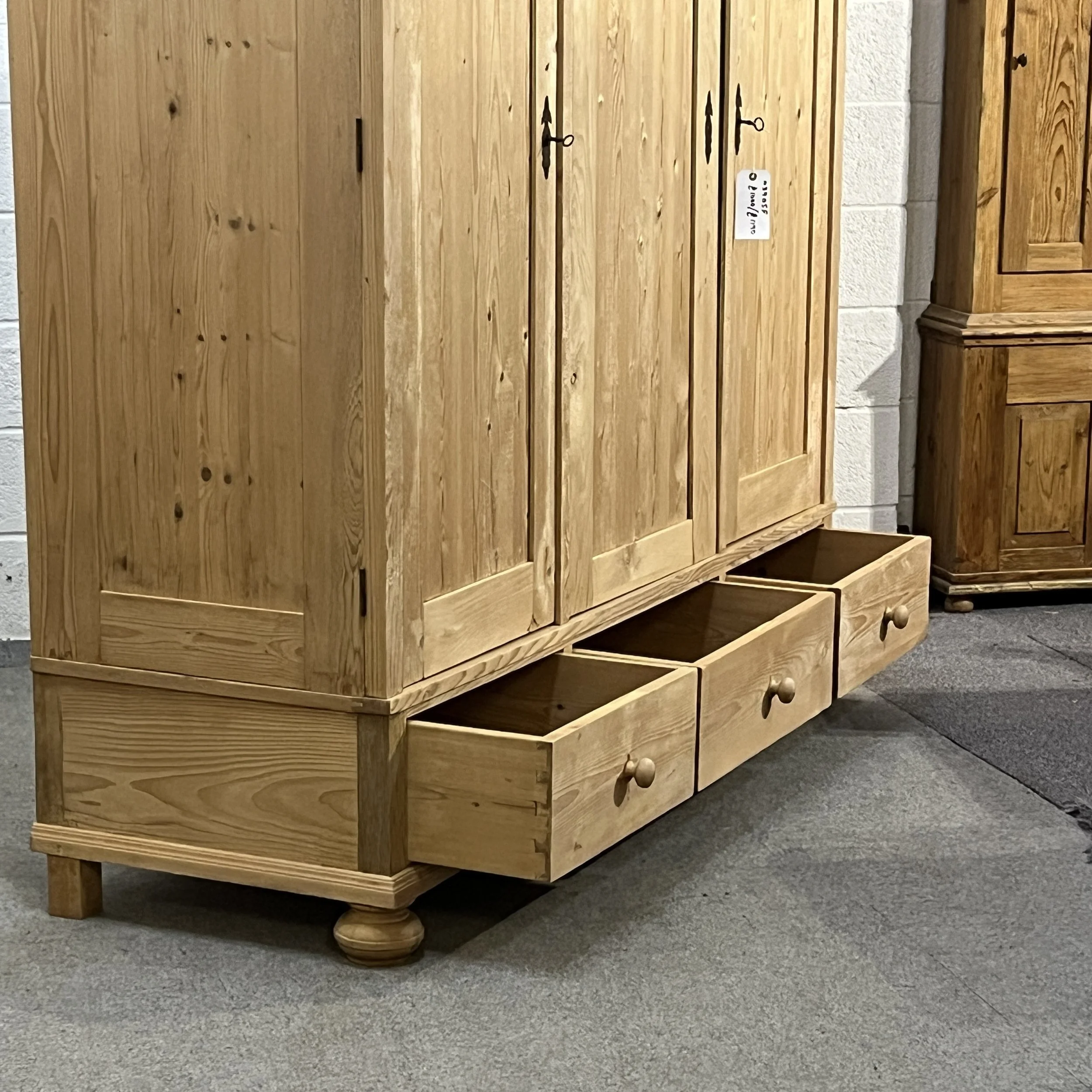 Pine triple wardrobe with its bottom drawers pulled open