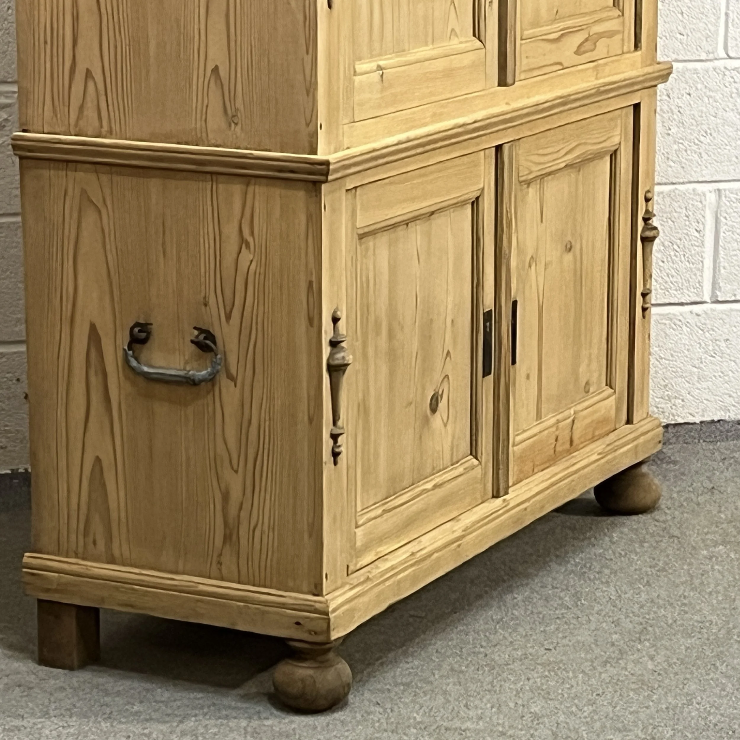 Detail of the pine campaign cupboard lower section, side handle and rounded foot