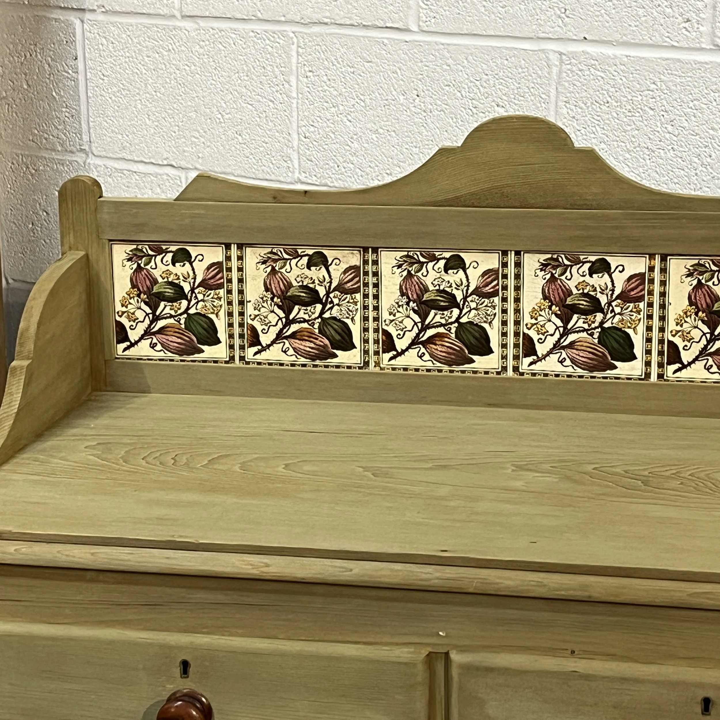 Close-up of the six original floral tiles and shaped gallery back on the Victorian pine chest