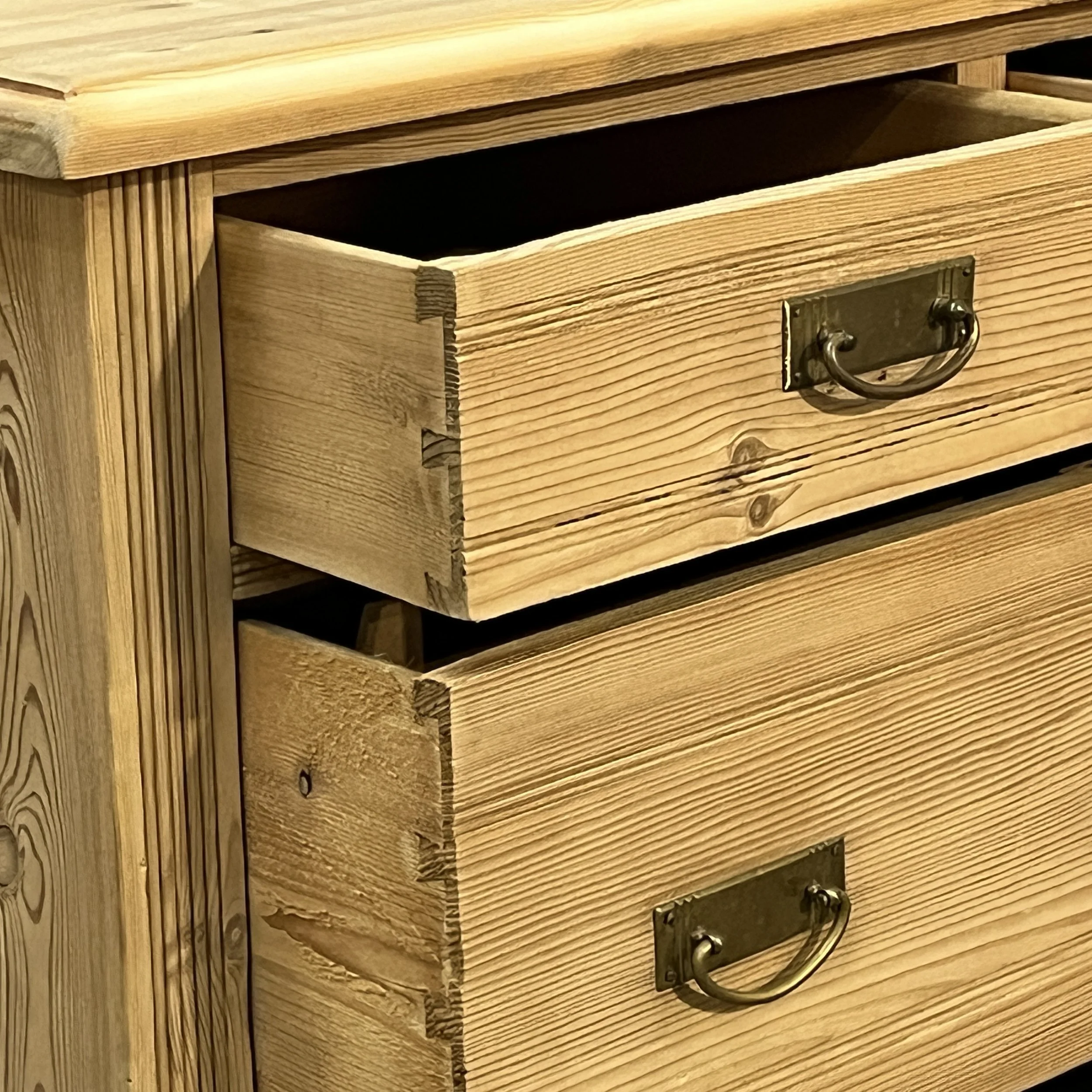 Close-up of N8004C chest drawer dovetail joints, brass drop handle and reeded front corner.
