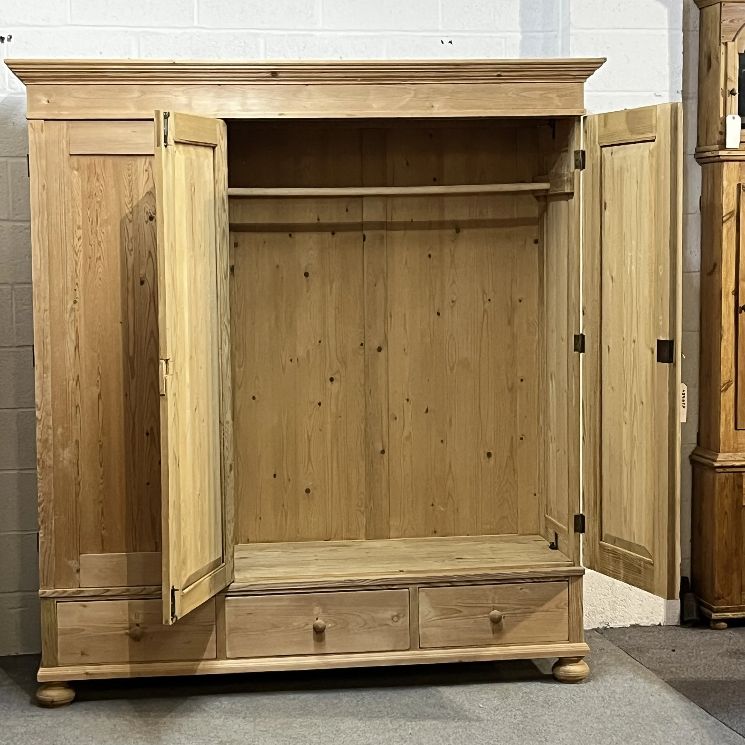 Pine triple wardrobe with central and right doors open to show hanging rail and shelf