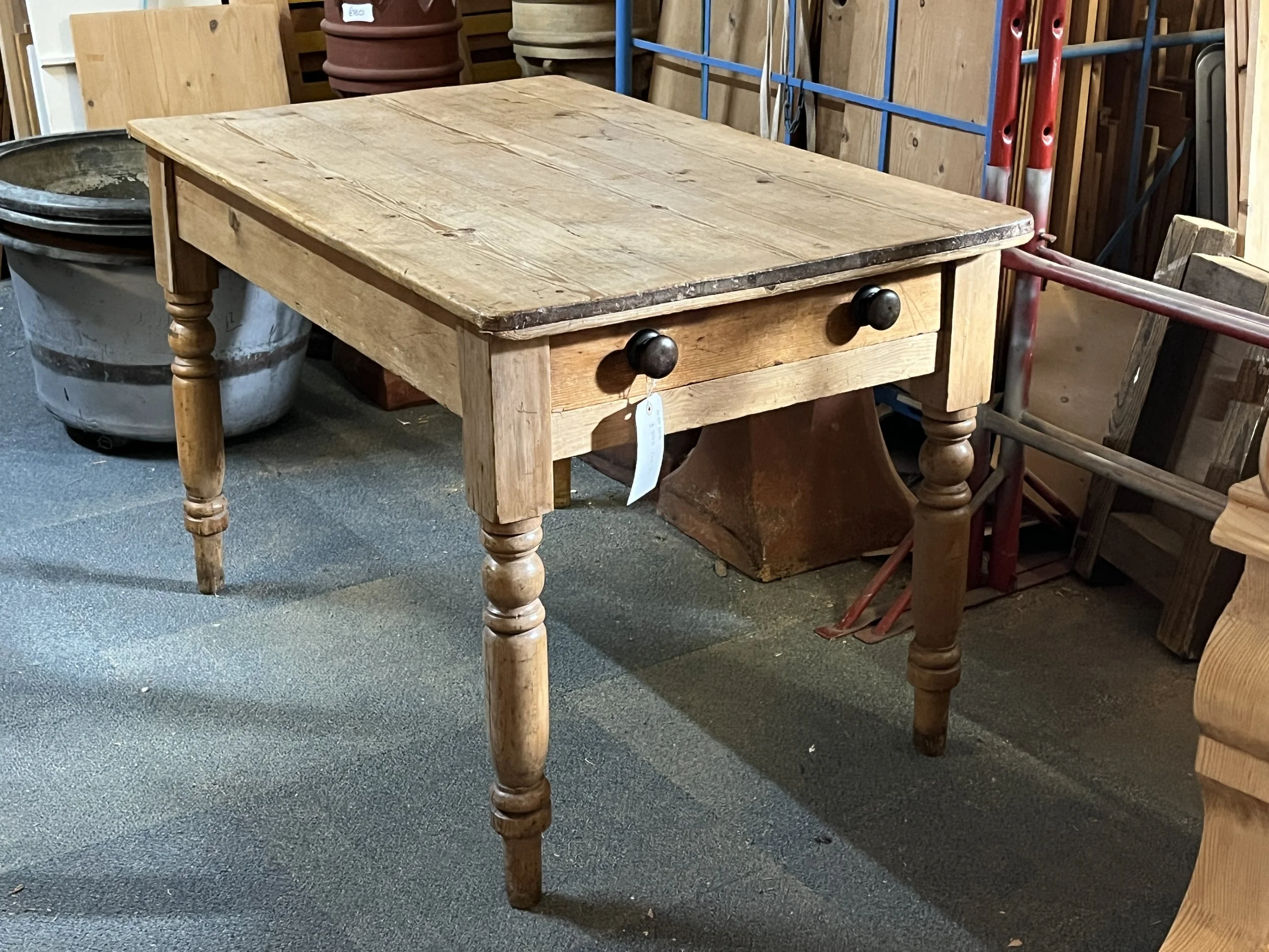 Small pine table viewed at an angle, with turned legs and an end drawer