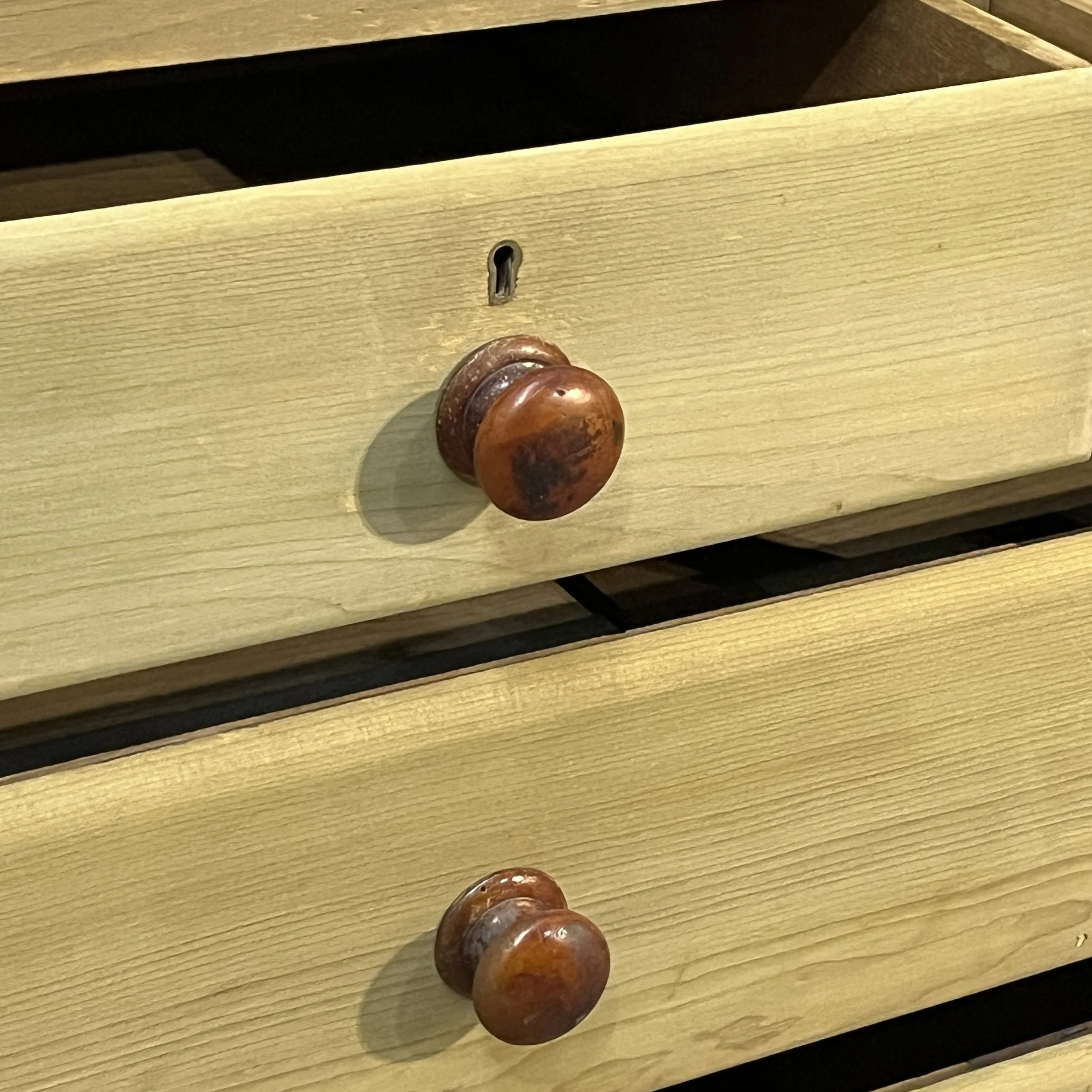 Close-up of an original dark wooden knob and keyhole on the Victorian pine chest