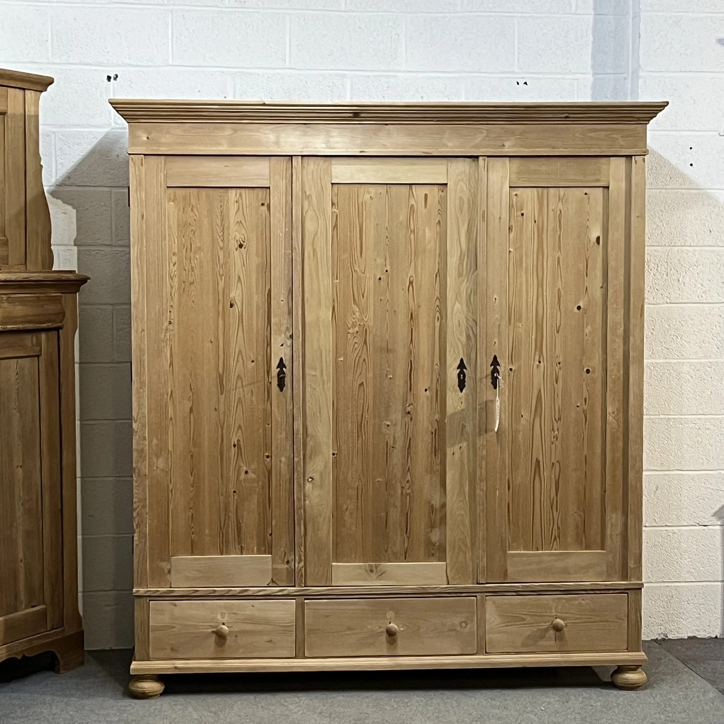 Front view of the triple pine wardrobe with three panelled doors and bottom drawers