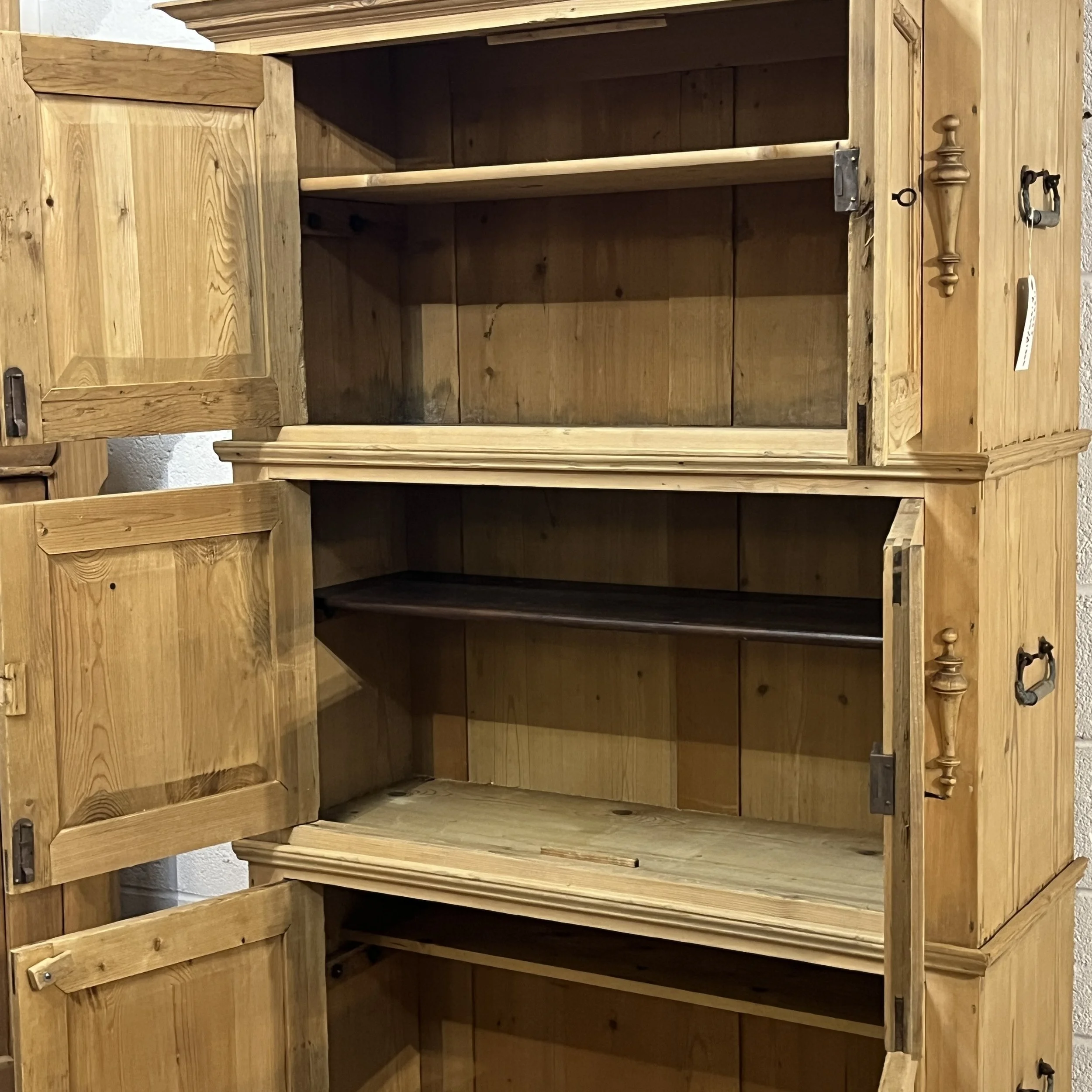Close-up of the open shelves and compartments inside the pine campaign cupboard