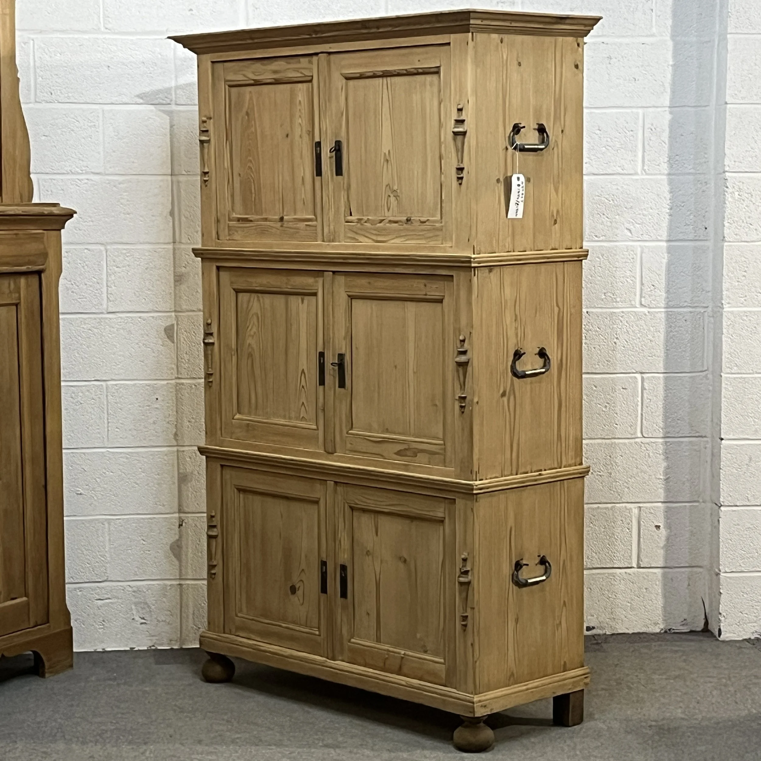 Angled view of the pine campaign cupboard showing its right side and carrying handles