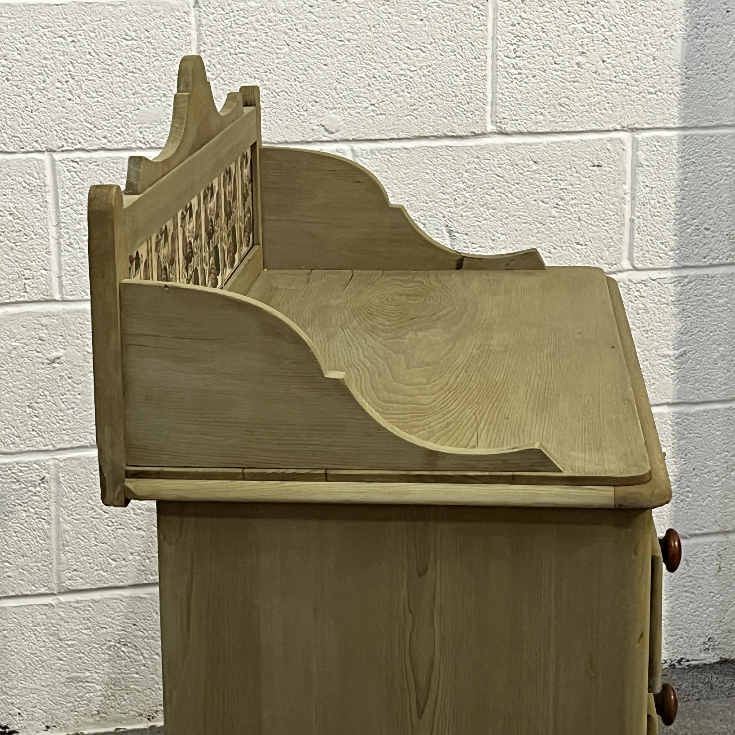 Side view showing the curved gallery support and pine grain on the Victorian chest of drawers
