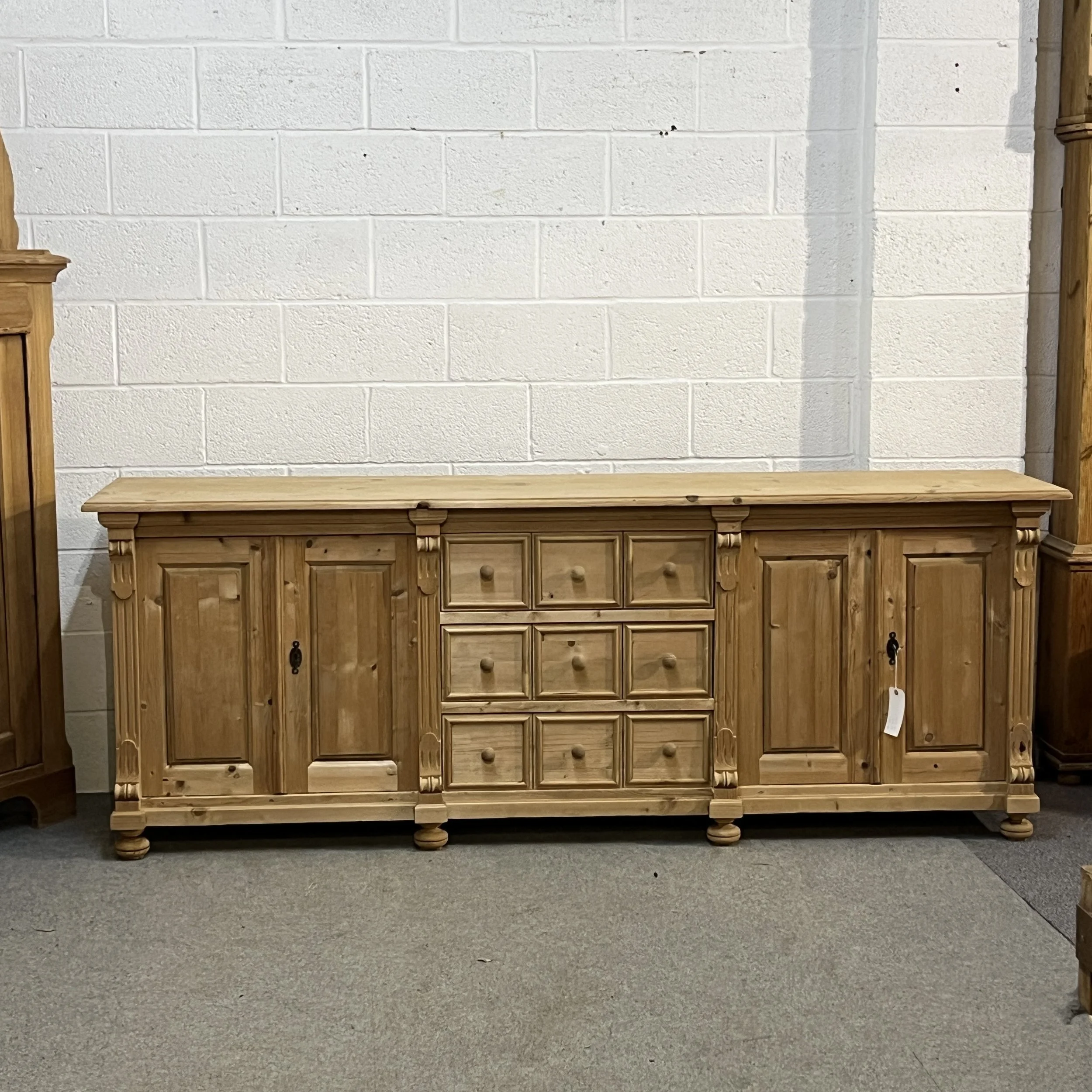 Pine sideboard N7102E viewed straight on, showing four doors, carved pilasters and bun feet