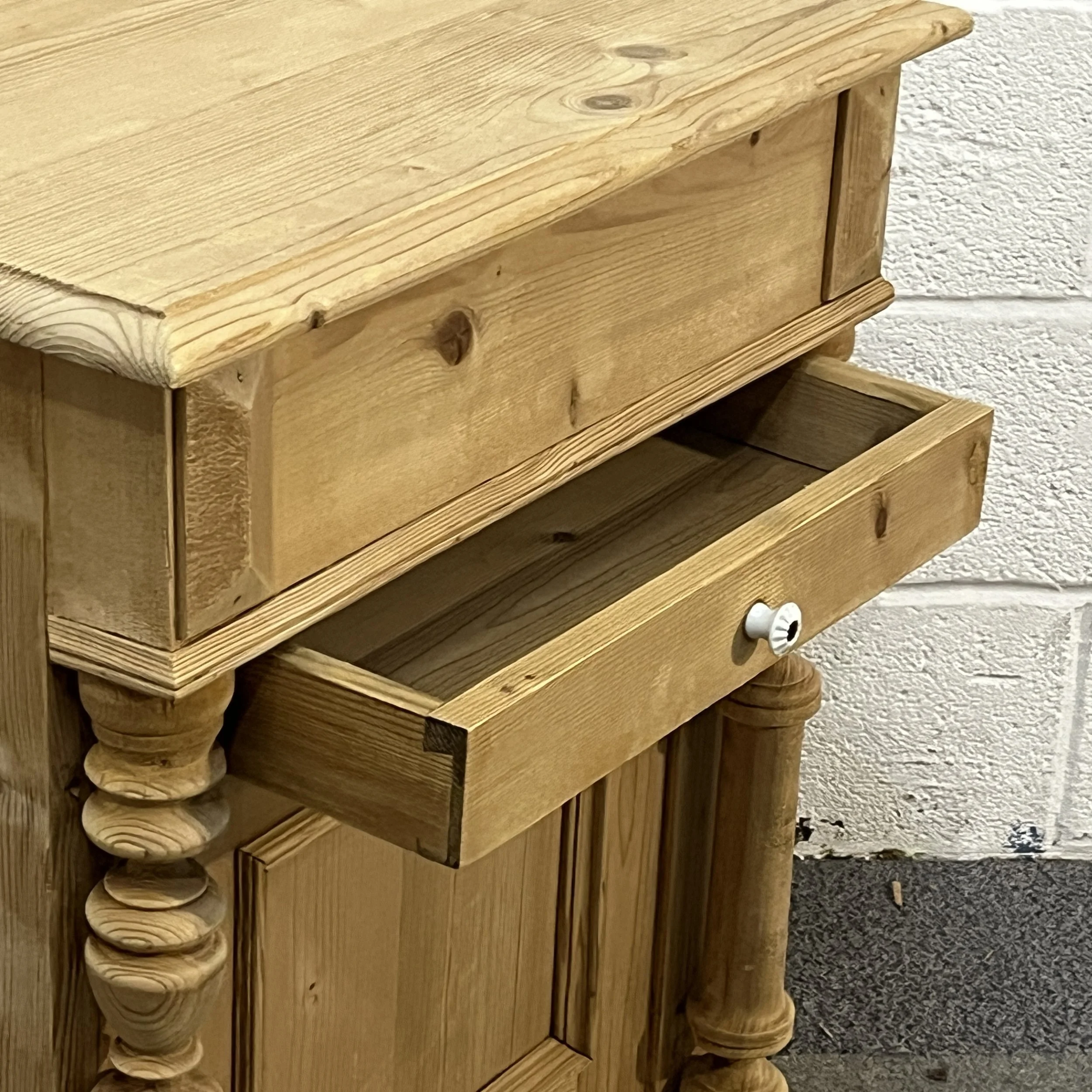 Open drawer with white porcelain knob on the antique pine wash cupboard