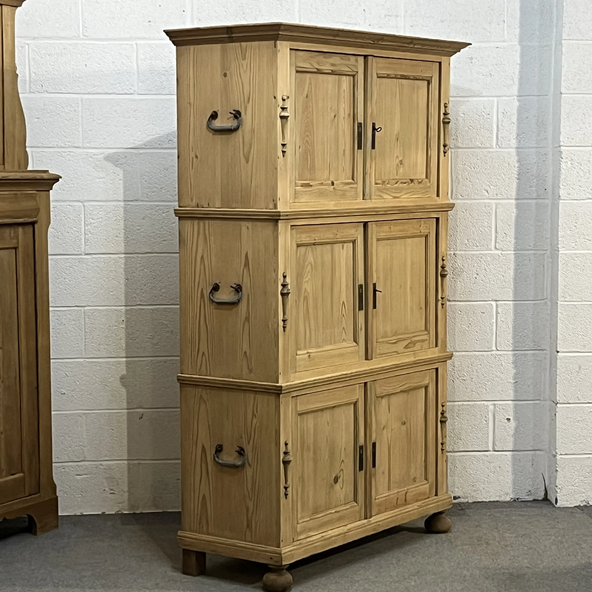 Opposite angled view of the pine campaign cupboard showing its left side and carrying handles