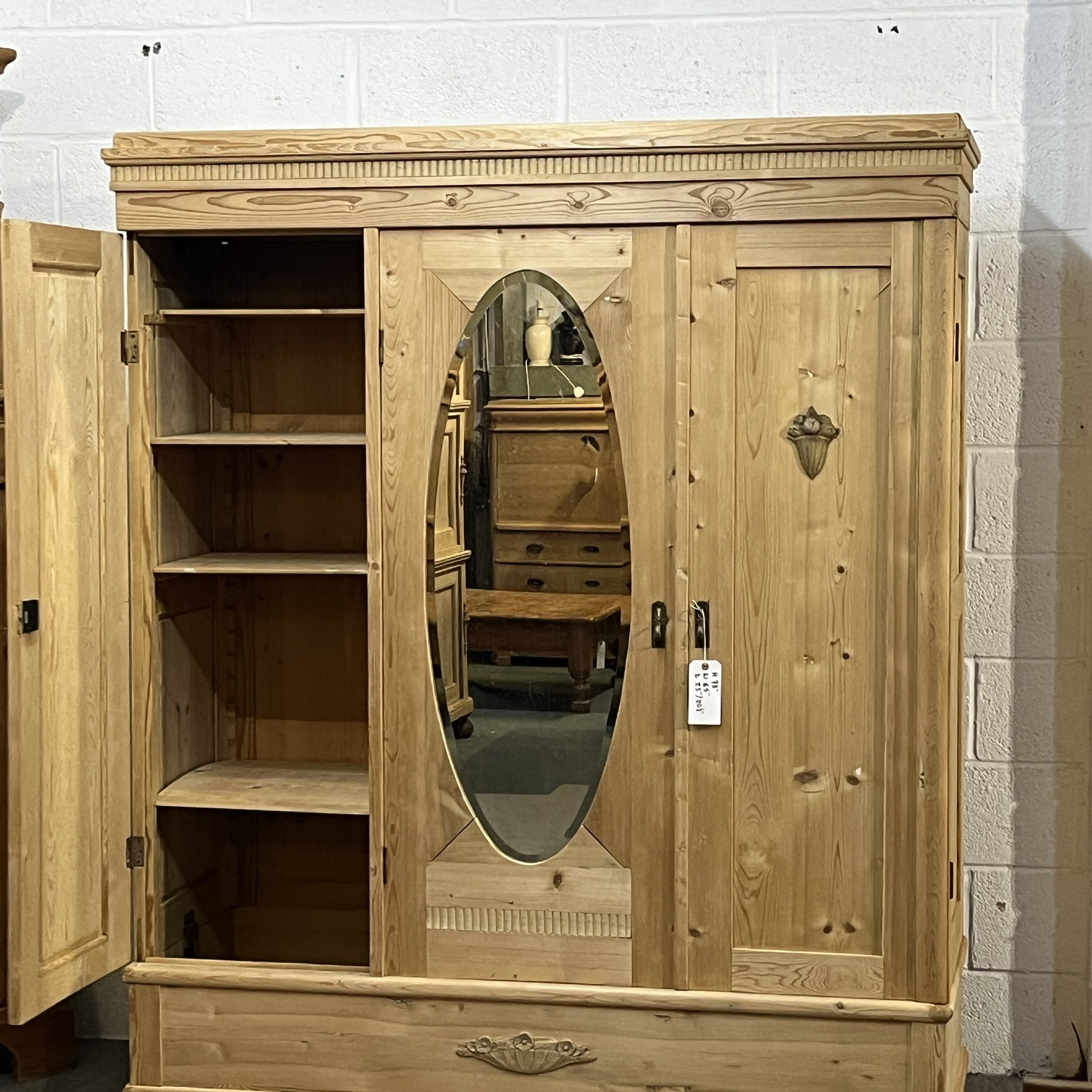 Pine wardrobe with left door open to reveal its shelved storage compartment