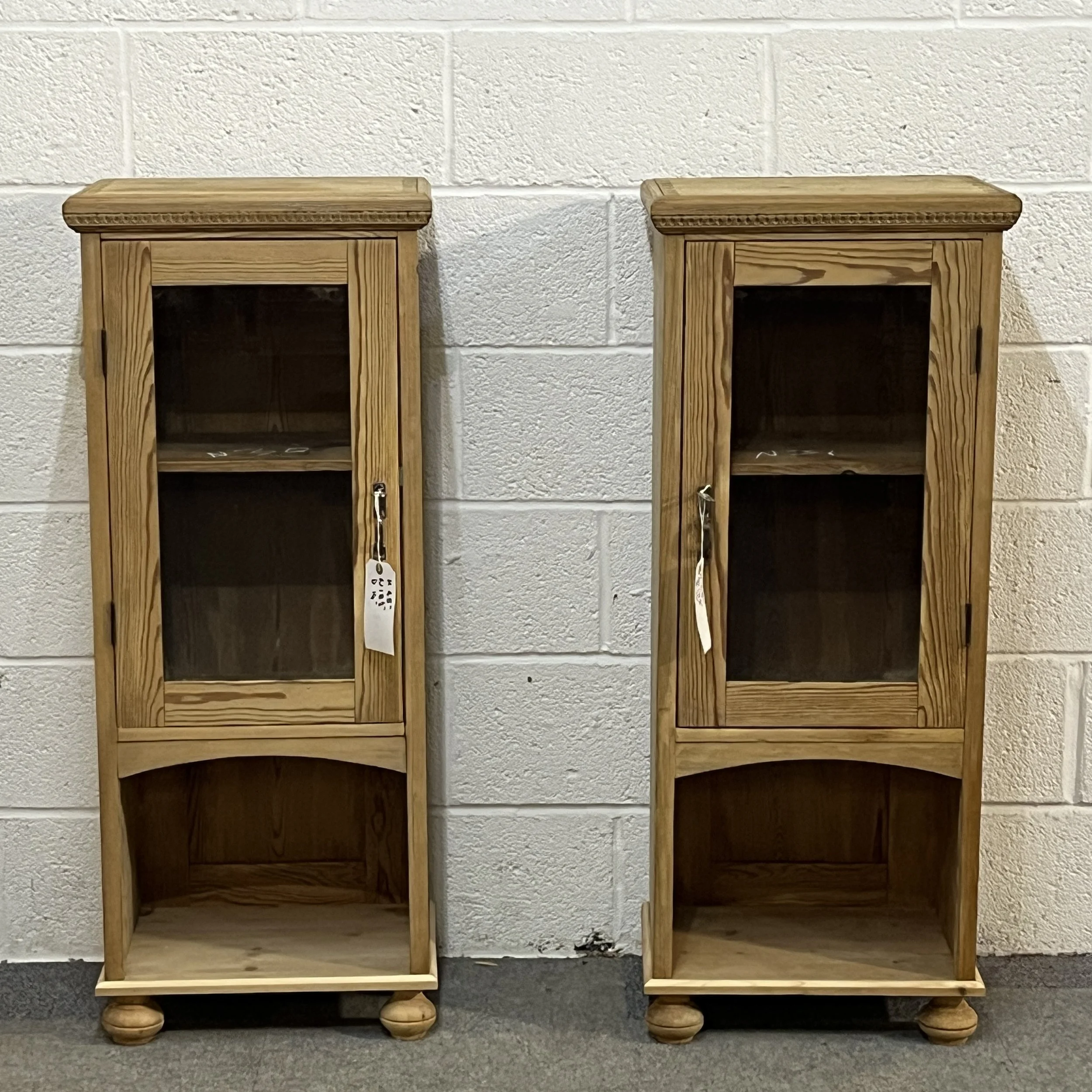 Front view of two slender pine glazed cabinets with open lower compartments