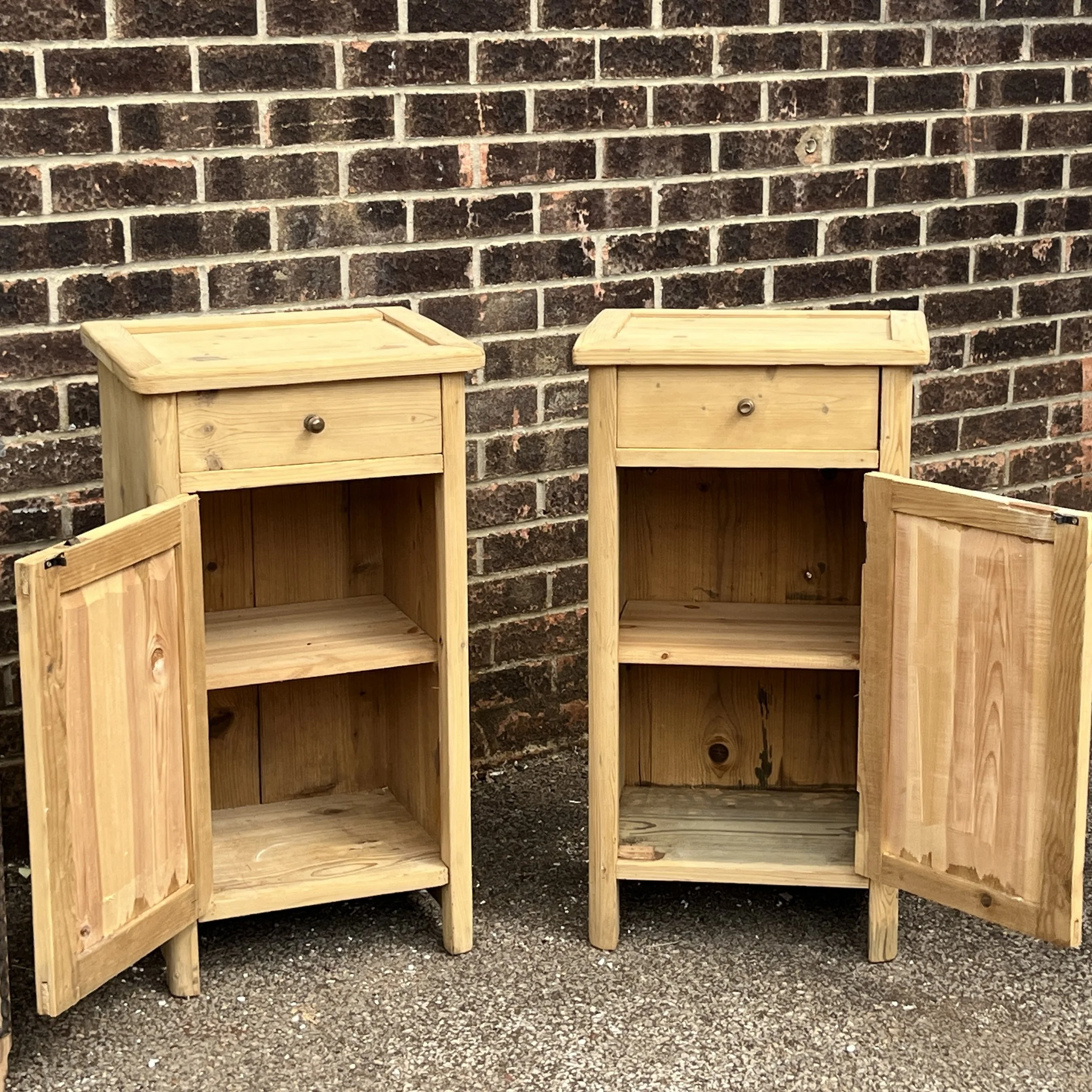 Pair of pine bedside cupboards with both doors open, showing their internal shelves