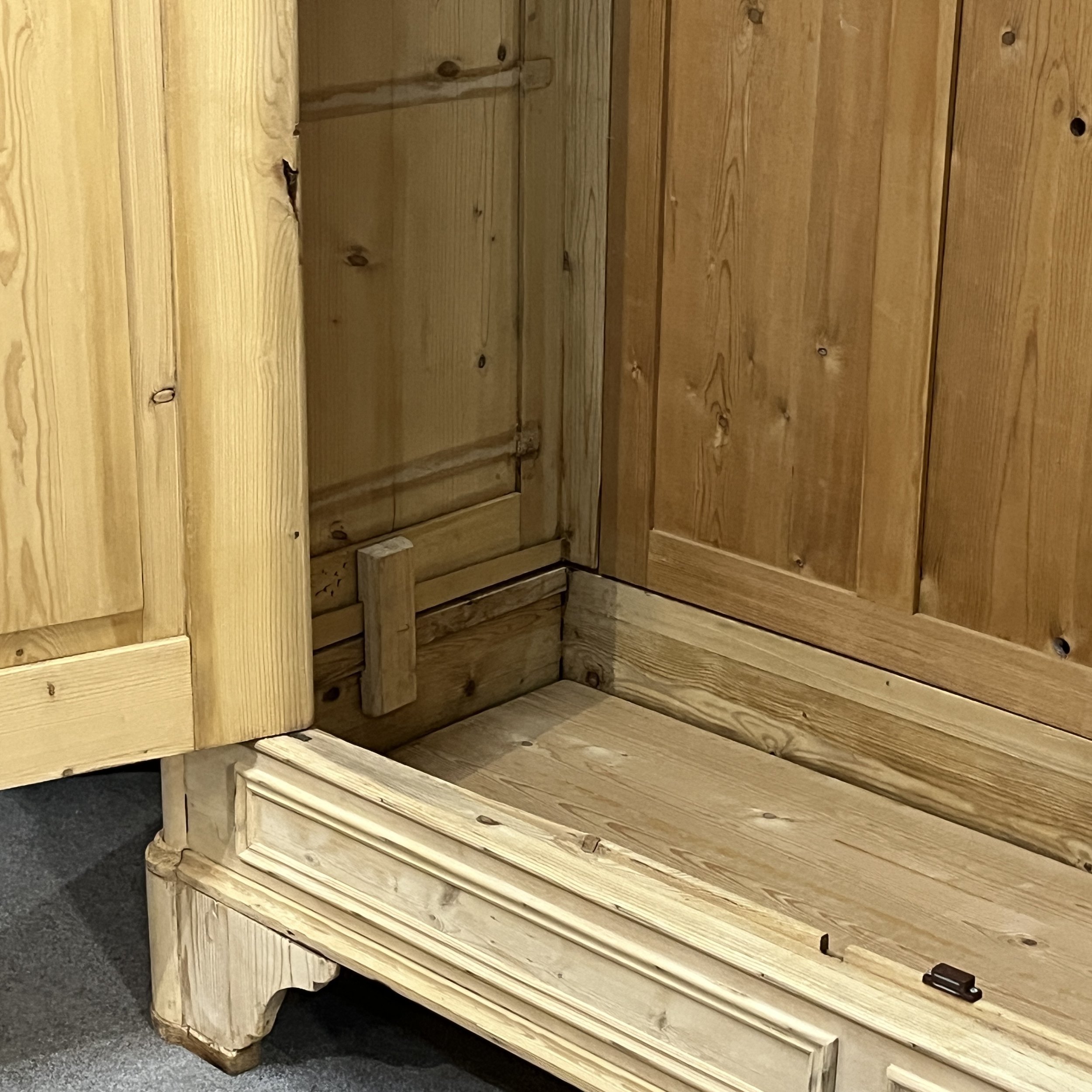 Detail inside the pine wardrobe showing the lower corner, door and wooden base
