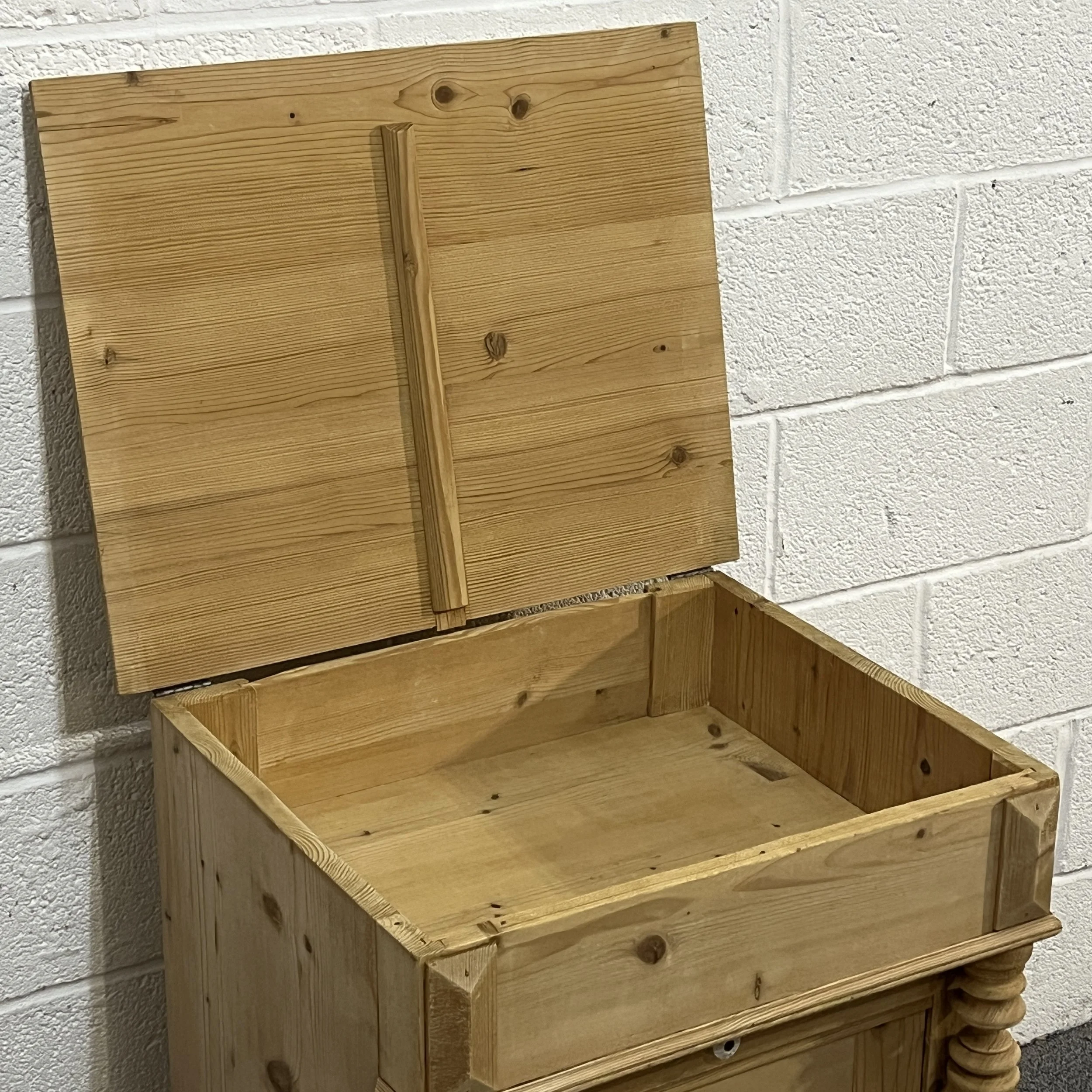 Close-up of the lift-up storage compartment in the pine wash cupboard
