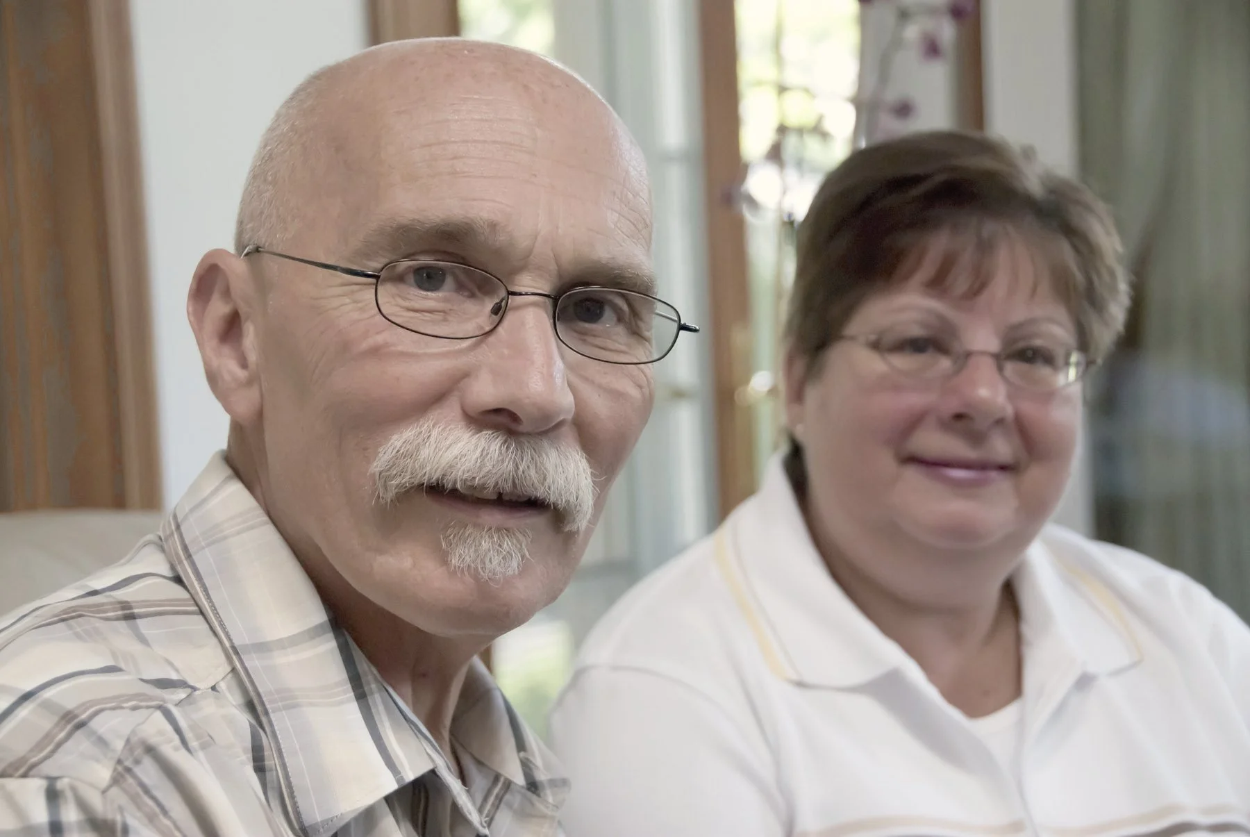 An older man and a woman sitting side by side, smiling.
