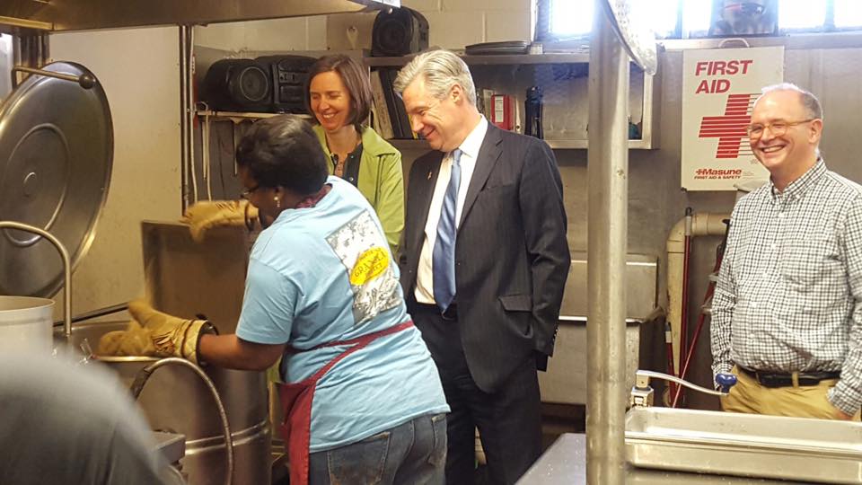 Senator Whitehouse watches as Bola adds the last of the dry ingredients. Keith and Anne look on.
