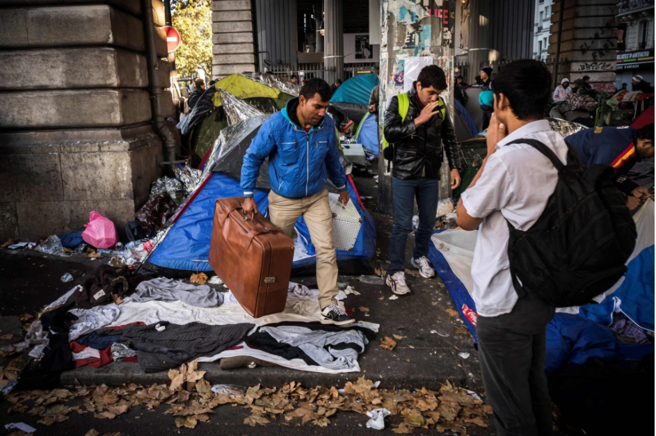 A migrant carrying his belongings at camp on Boulevard de la Villette in northern Paris. Credit Lionel Bonaventure/Agence France-Presse — Getty Images