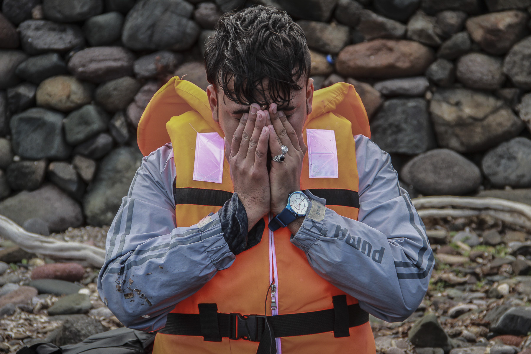   A Syrian refugee sinks to his knees moments after arriving safely to the shores of Lesvos. The boat that left before his never made it and at least another 33 refugees drowned in the Aegean that day. October 2015.  