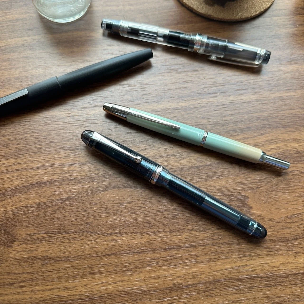 Three different fountain pens sitting on a desk freshly used.